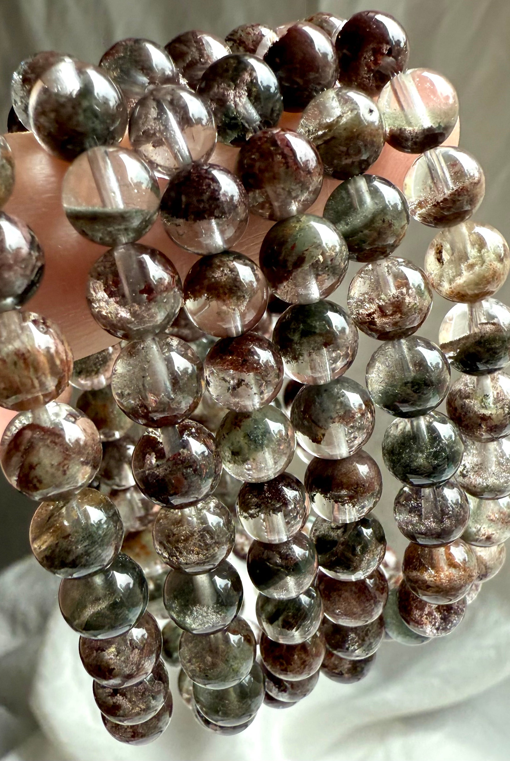 Detailed view of round Garden Quartz beads showing red, green, and brown chlorite phantoms