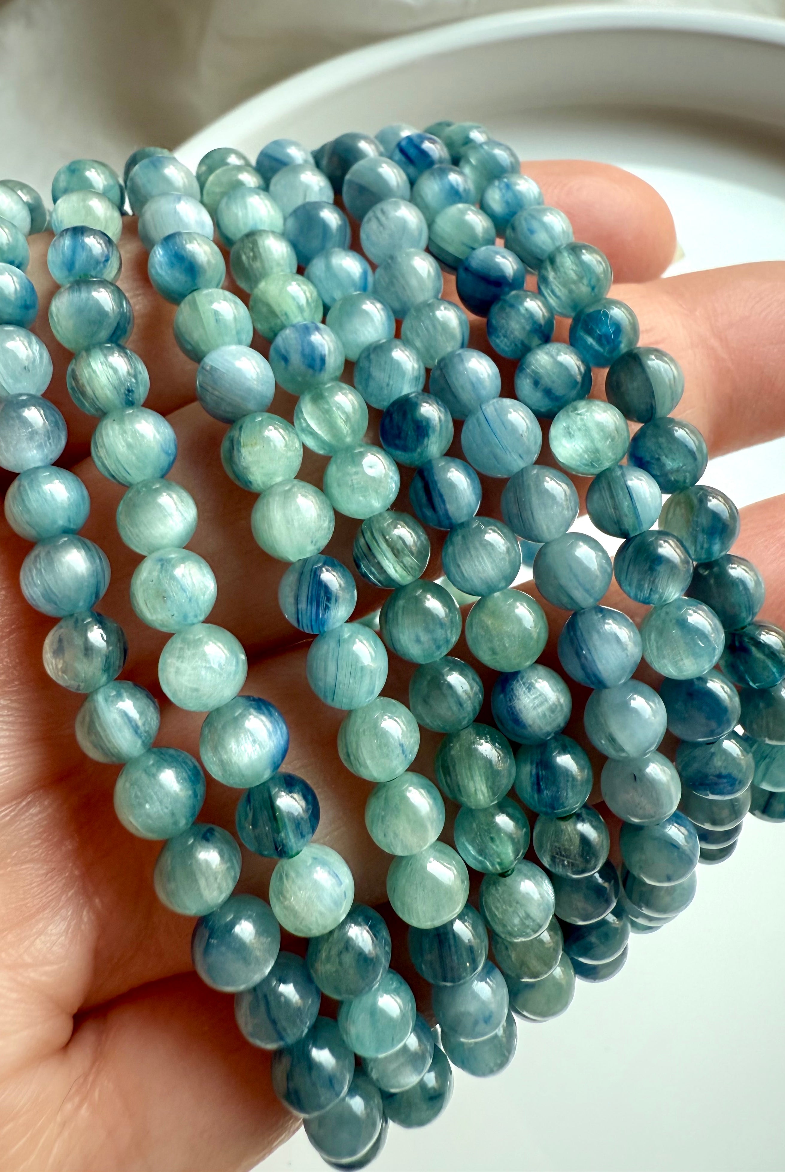 crystal bracelets arranged on hand with luminous banded blue-green kyanite beads for clarity and energy flow