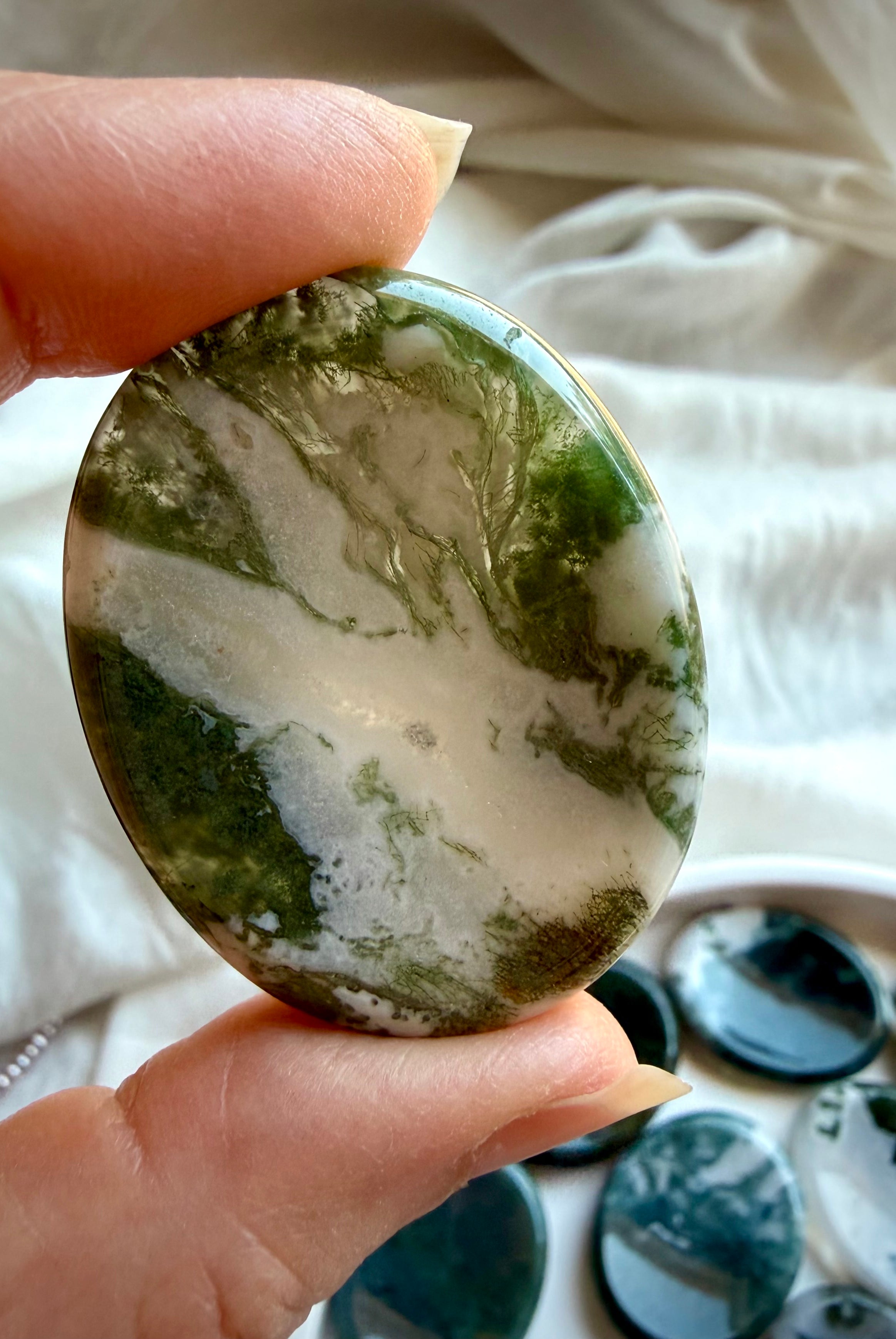 Large Moss Agate oval worry stone held in hand with clear quartz windows and green landscape patterns