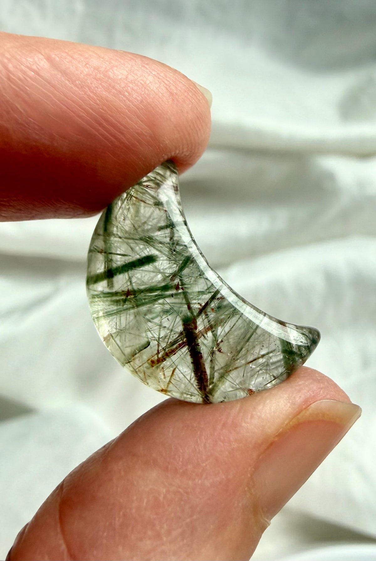Green Tourmaline Quartz crescent moon held in hand with dense needle-like inclusions and translucent polished quartz