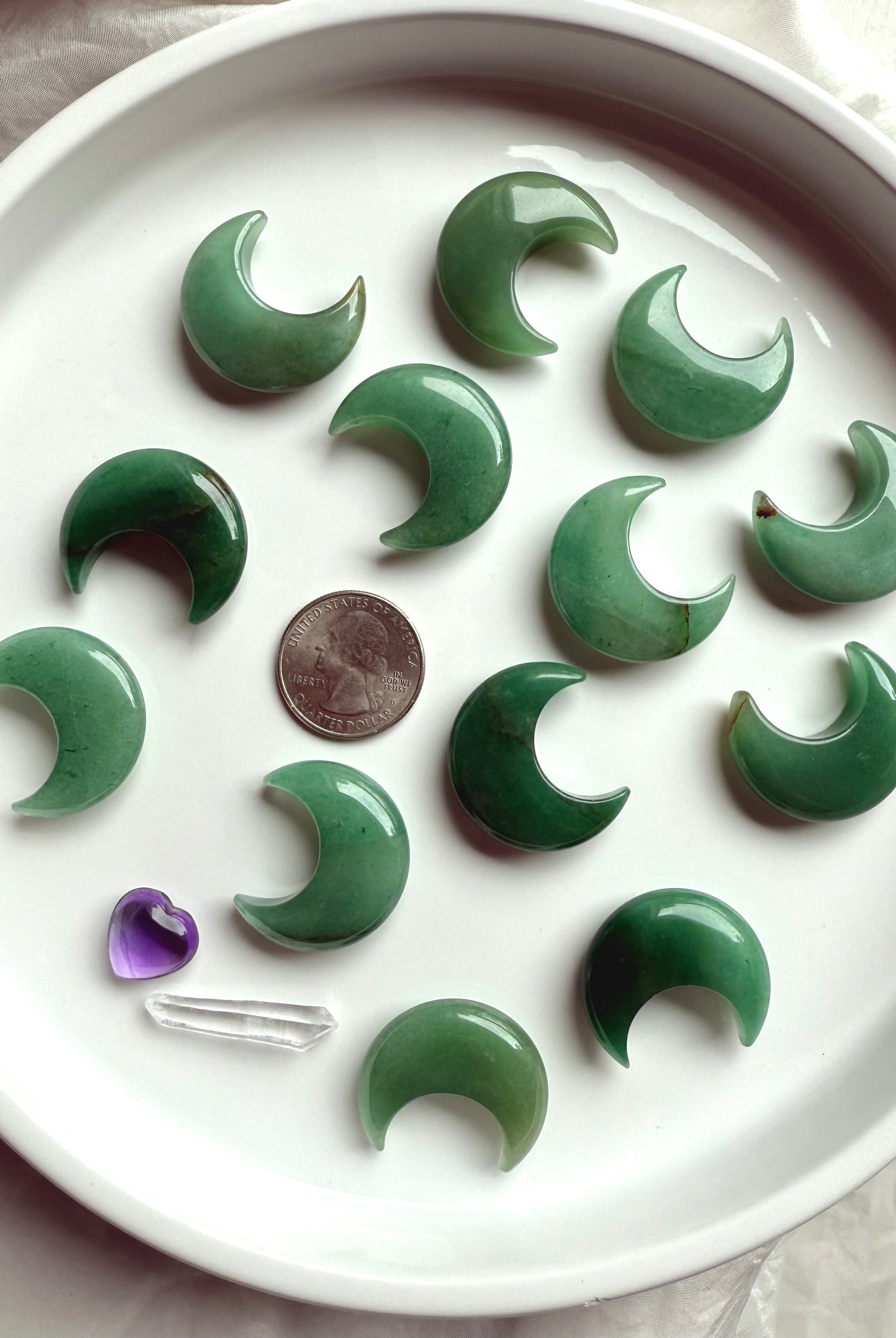 Flatlay of Green Aventurine moons on white plate with quarter for scale, crystal carvings for altar décor and meditation