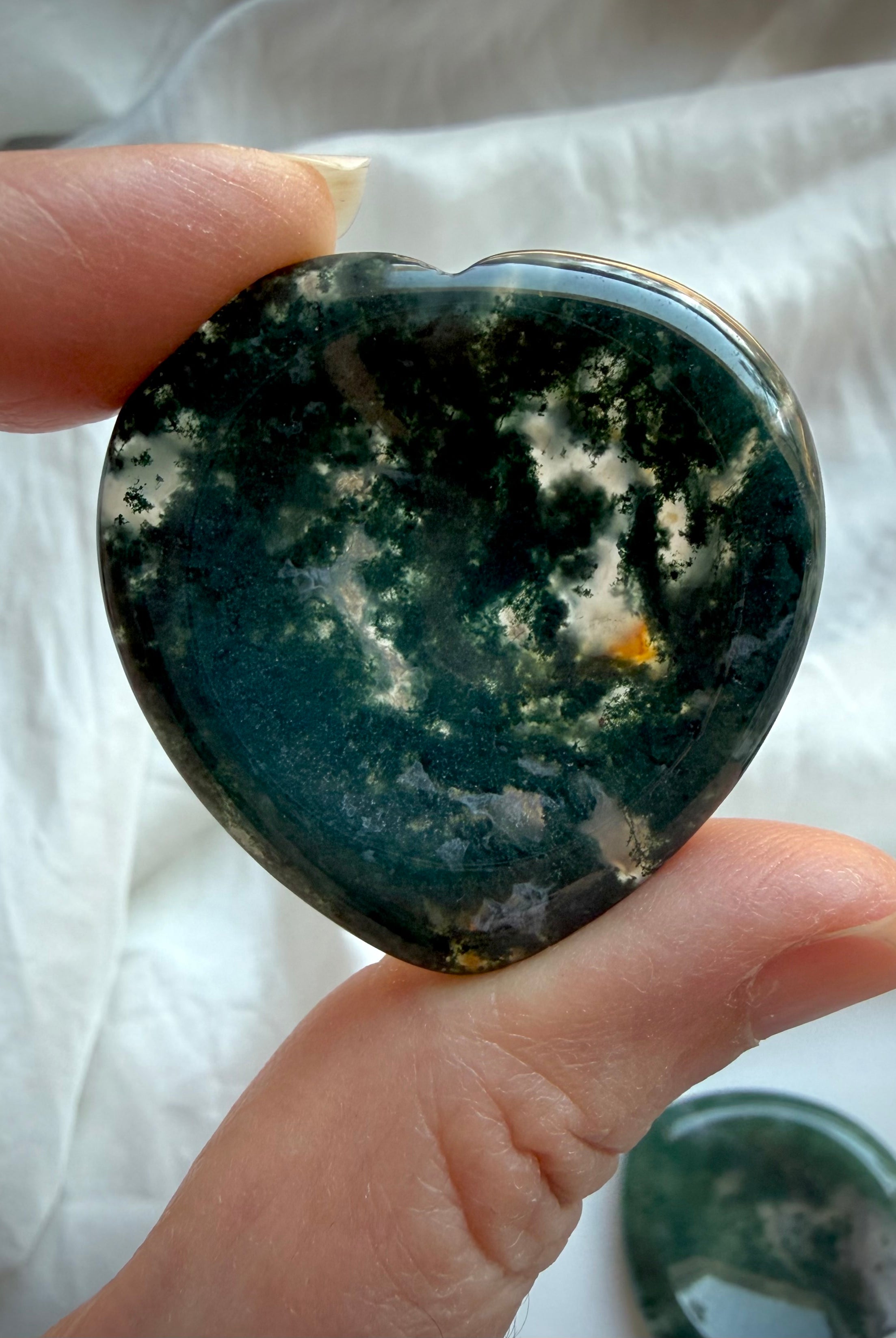 Dark green Moss Agate heart worry stone held in hand with polished natural crystal surface