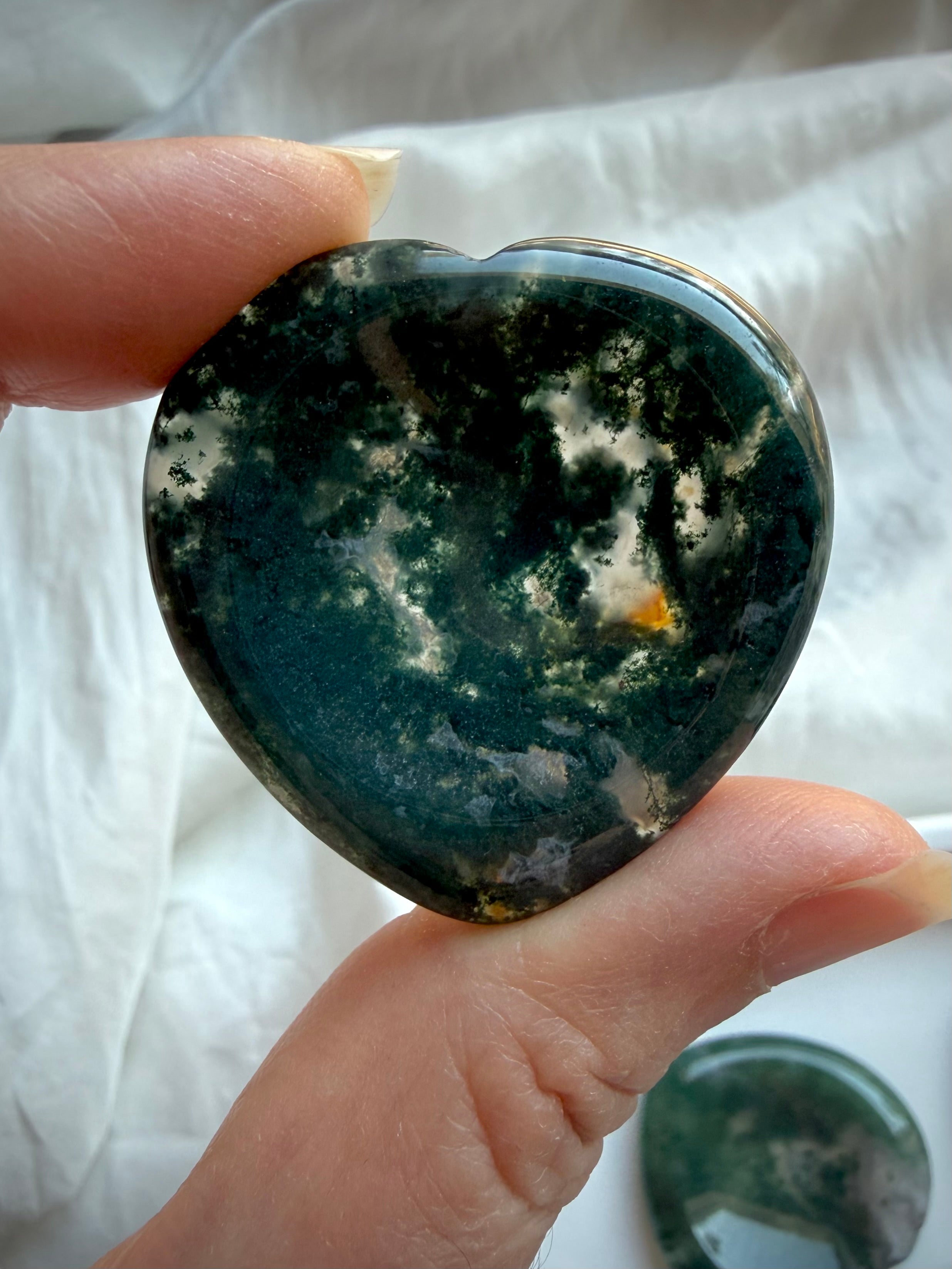 Dark green Moss Agate heart worry stone held in hand with polished natural crystal surface