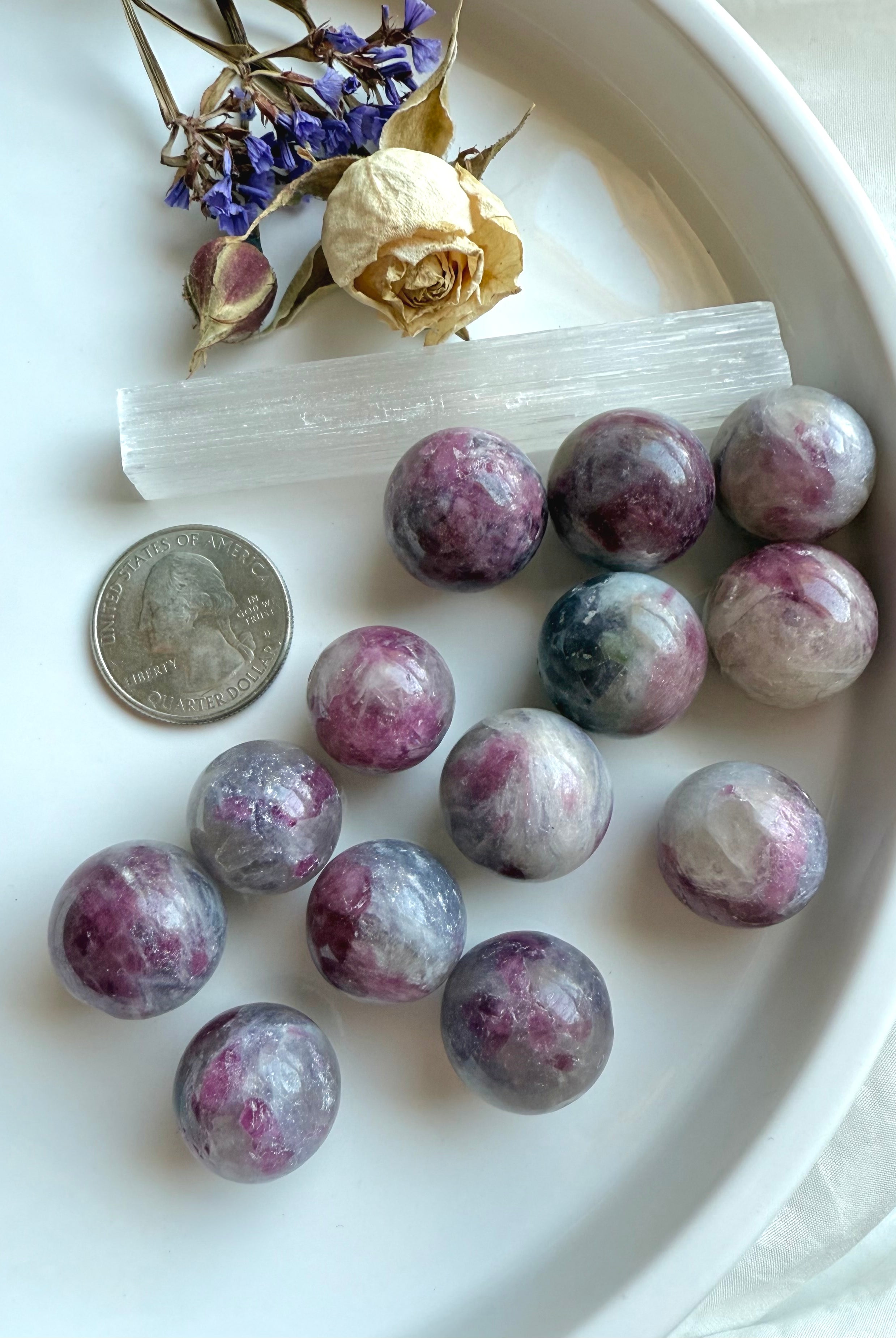 Mini Unicorn Stone spheres with a US quarter for size reference, styled with selenite wand and flowers