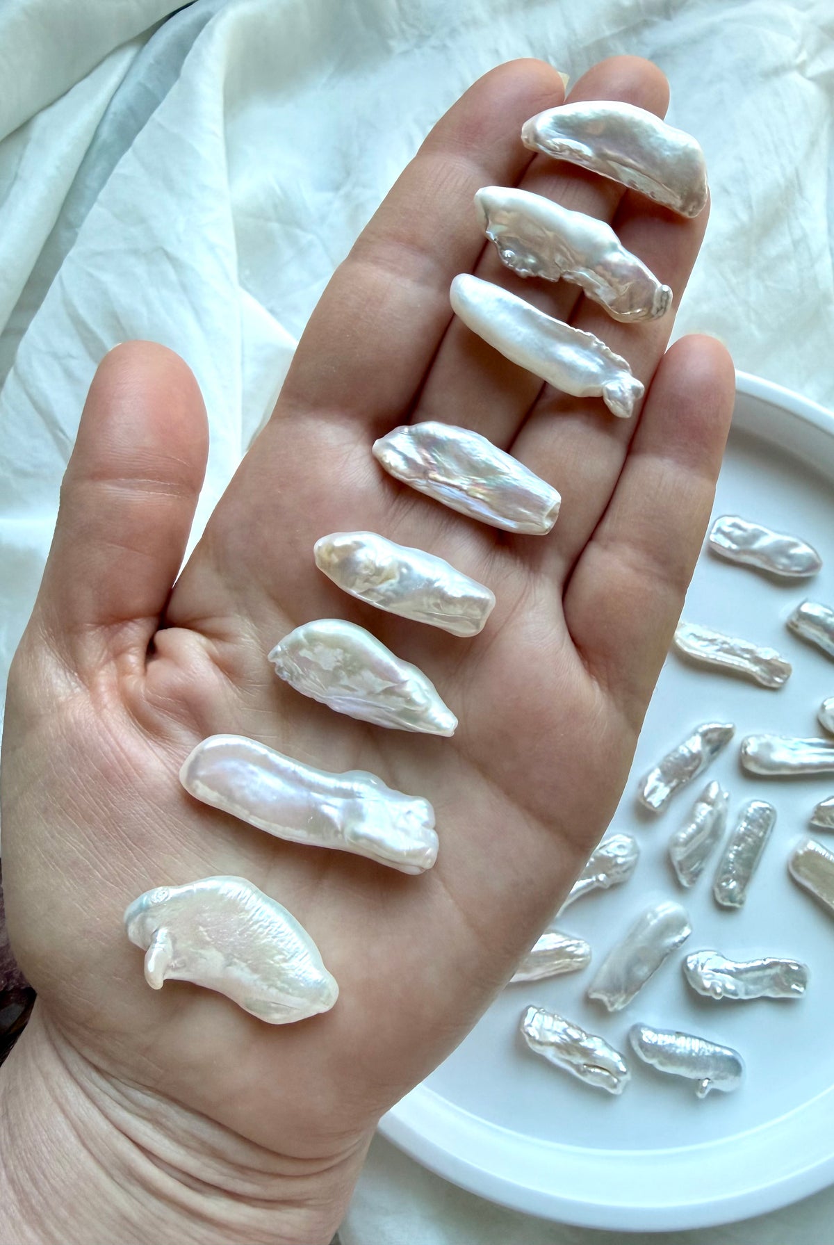Baroque Stick Pearls held in hand showing differences in length, shape, curvature and high-luster nacre