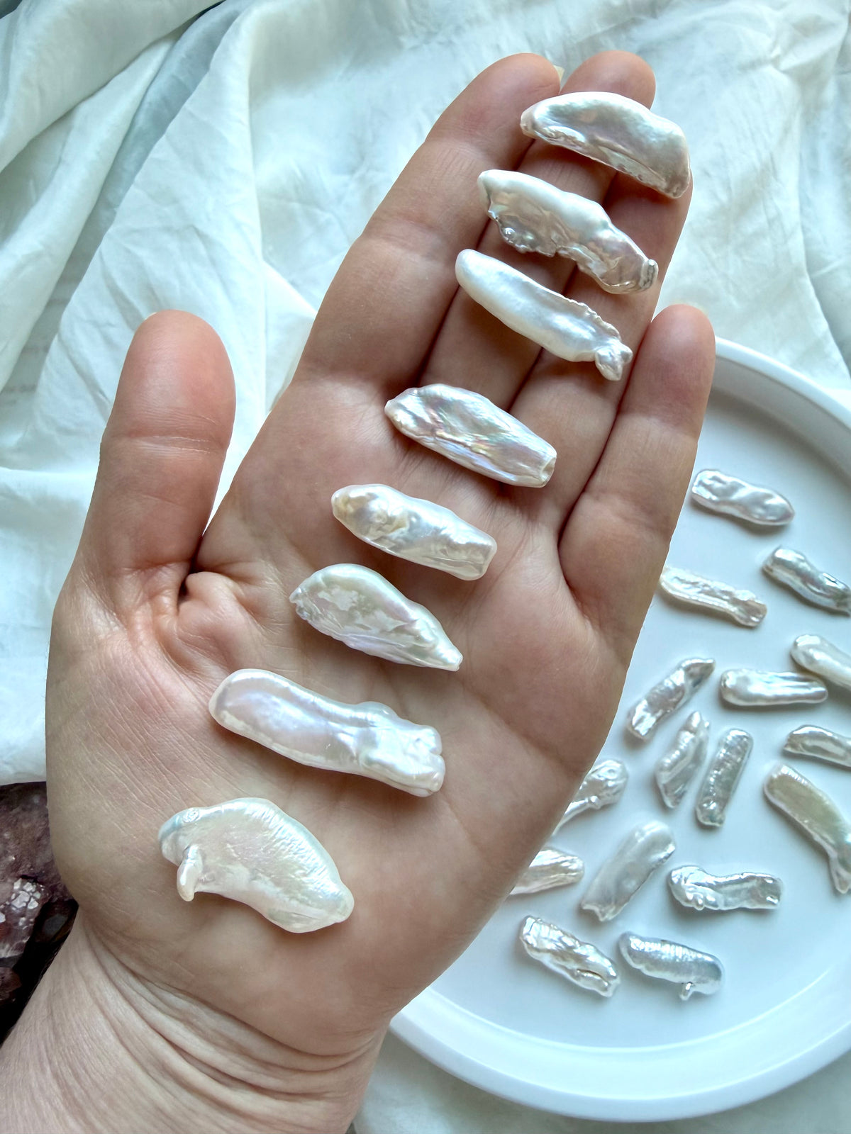 Baroque Stick Pearls held in hand showing differences in length, shape, curvature and high-luster nacre