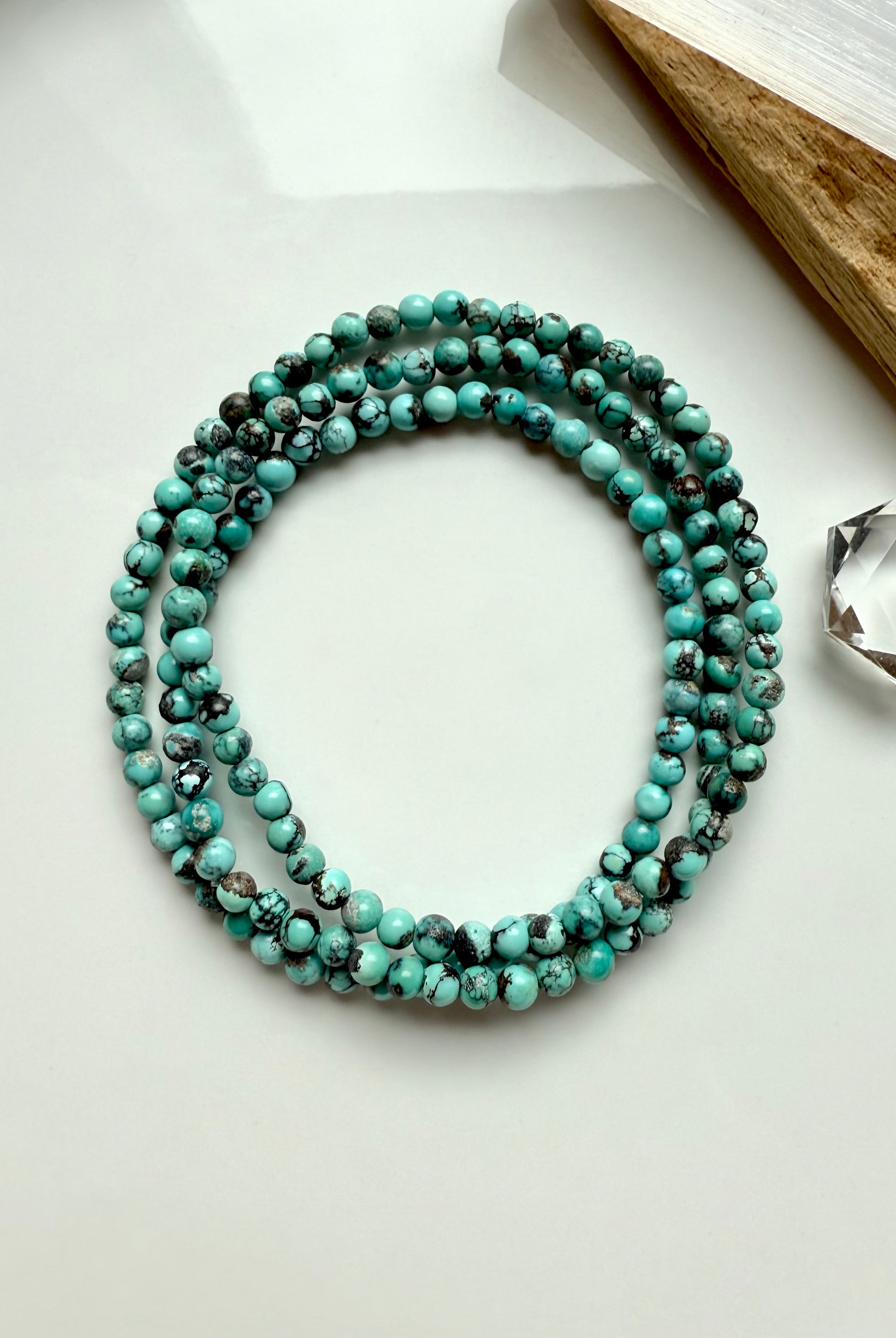 Natural Chinese Turquoise gemstone wrap bracelet laid in a circle on white background with earthy matrix and soft sage green tones