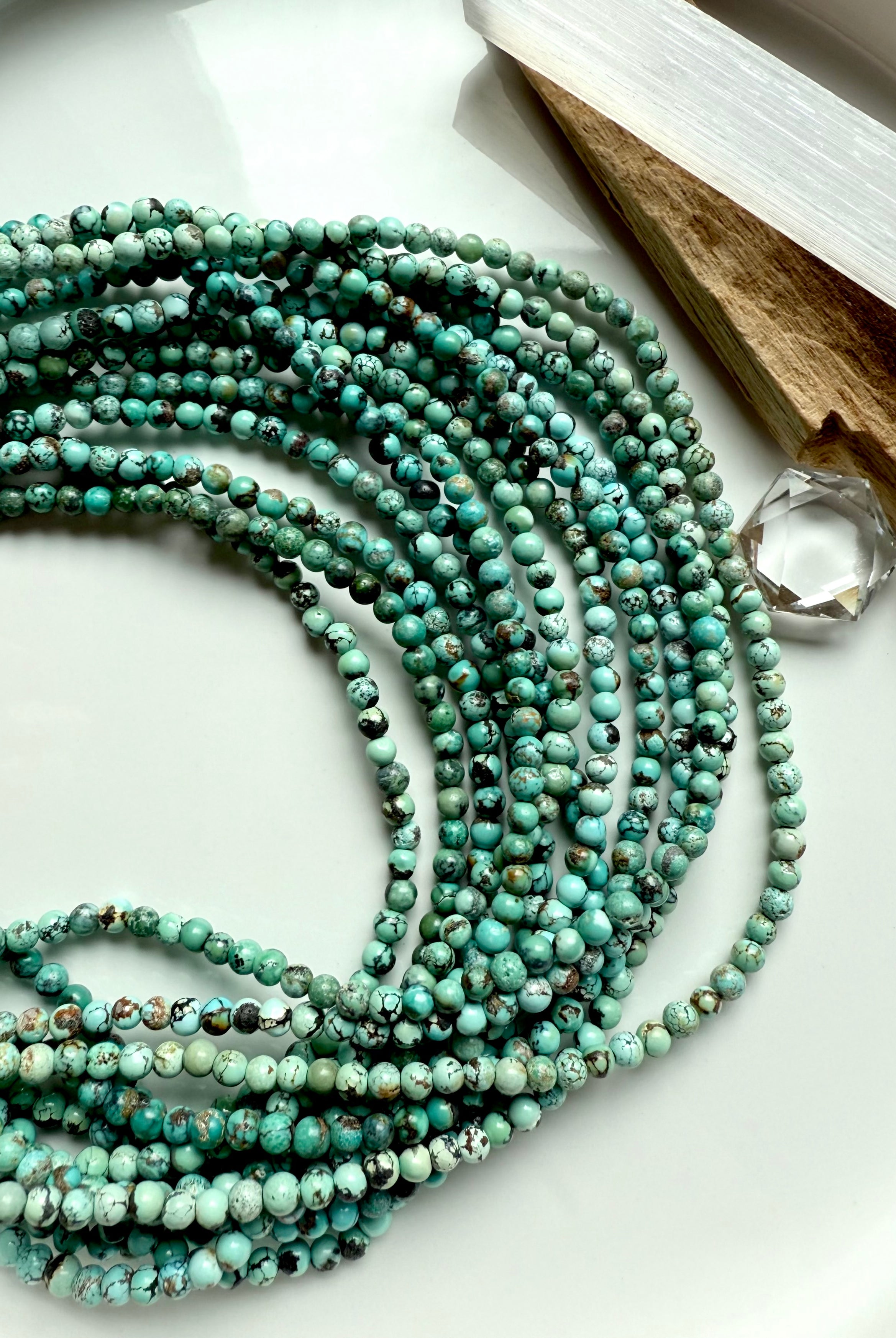 Artistic flat lay of Hubei Turquoise bracelets with selenite stick and crystal, featuring richly colored turquoise jasper beads