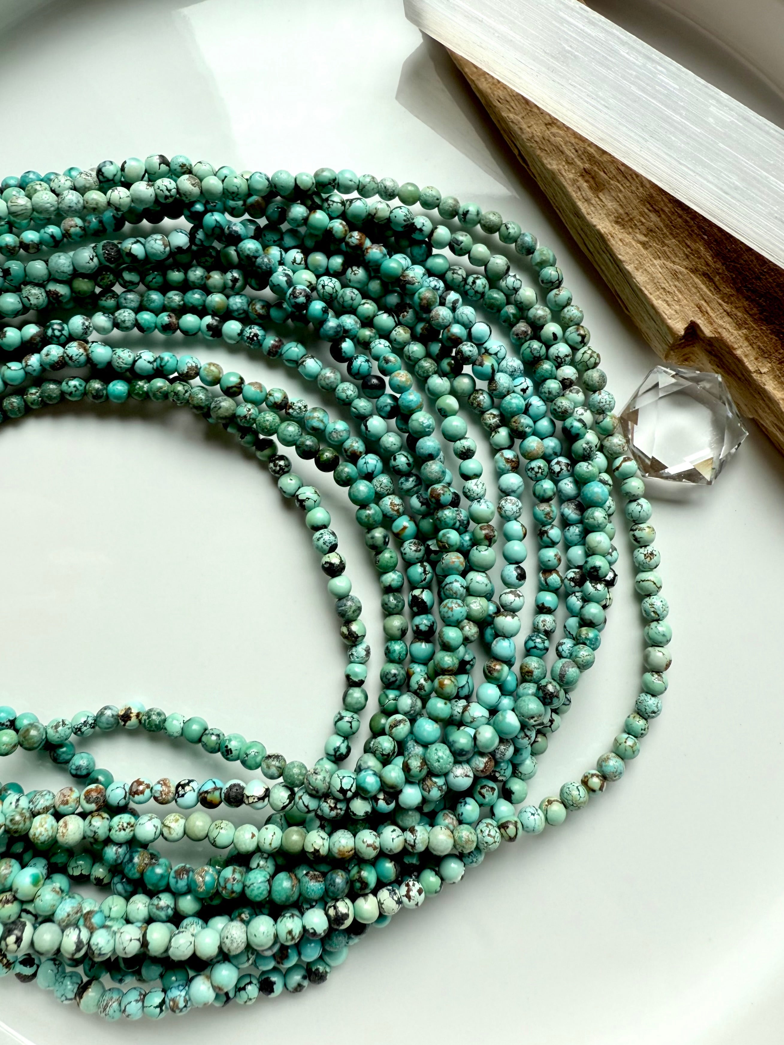 Artistic flat lay of Hubei Turquoise bracelets with selenite stick and crystal, featuring richly colored turquoise jasper beads