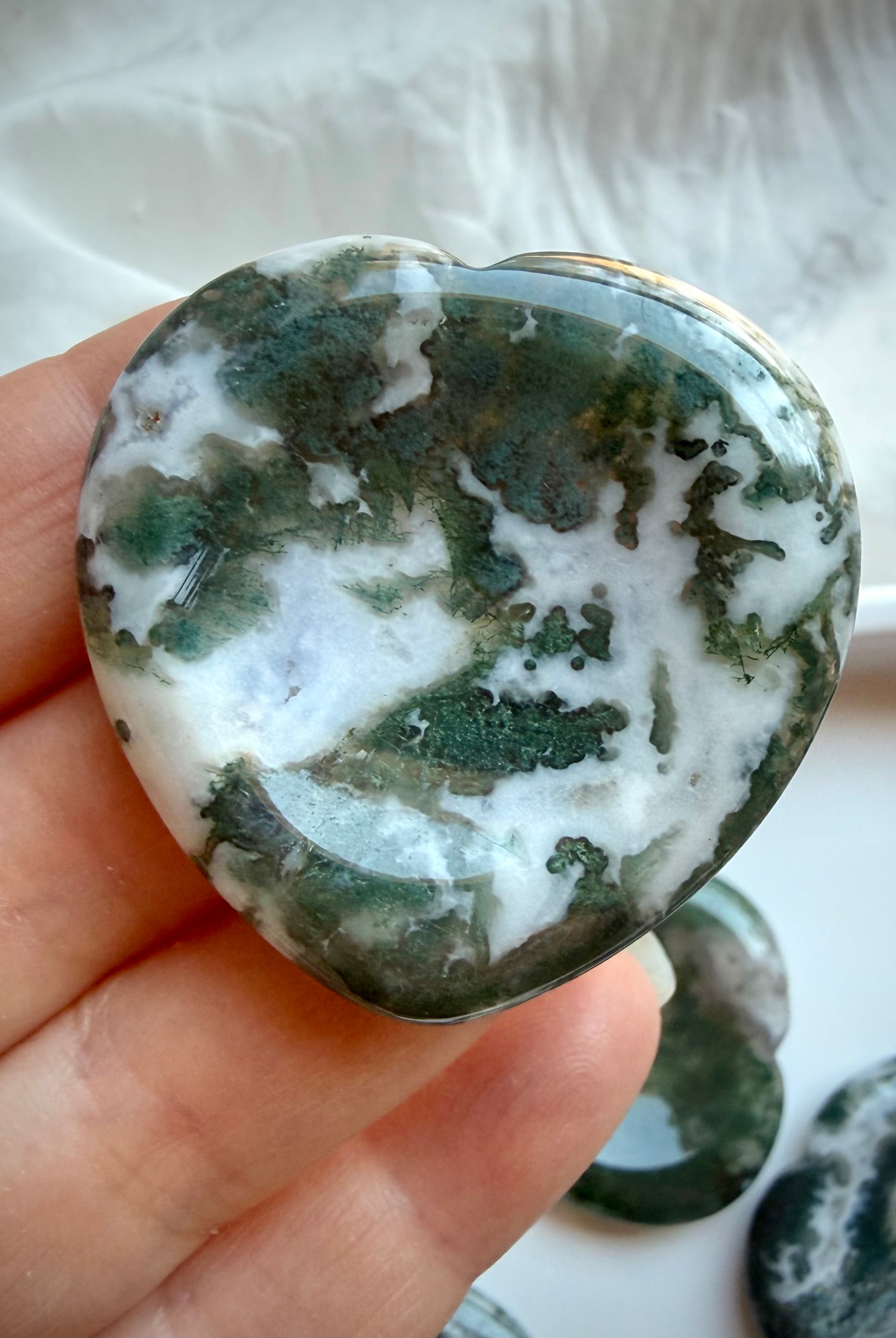 Large Moss Agate heart worry stone held in hand with white quartz and green landscape patterns