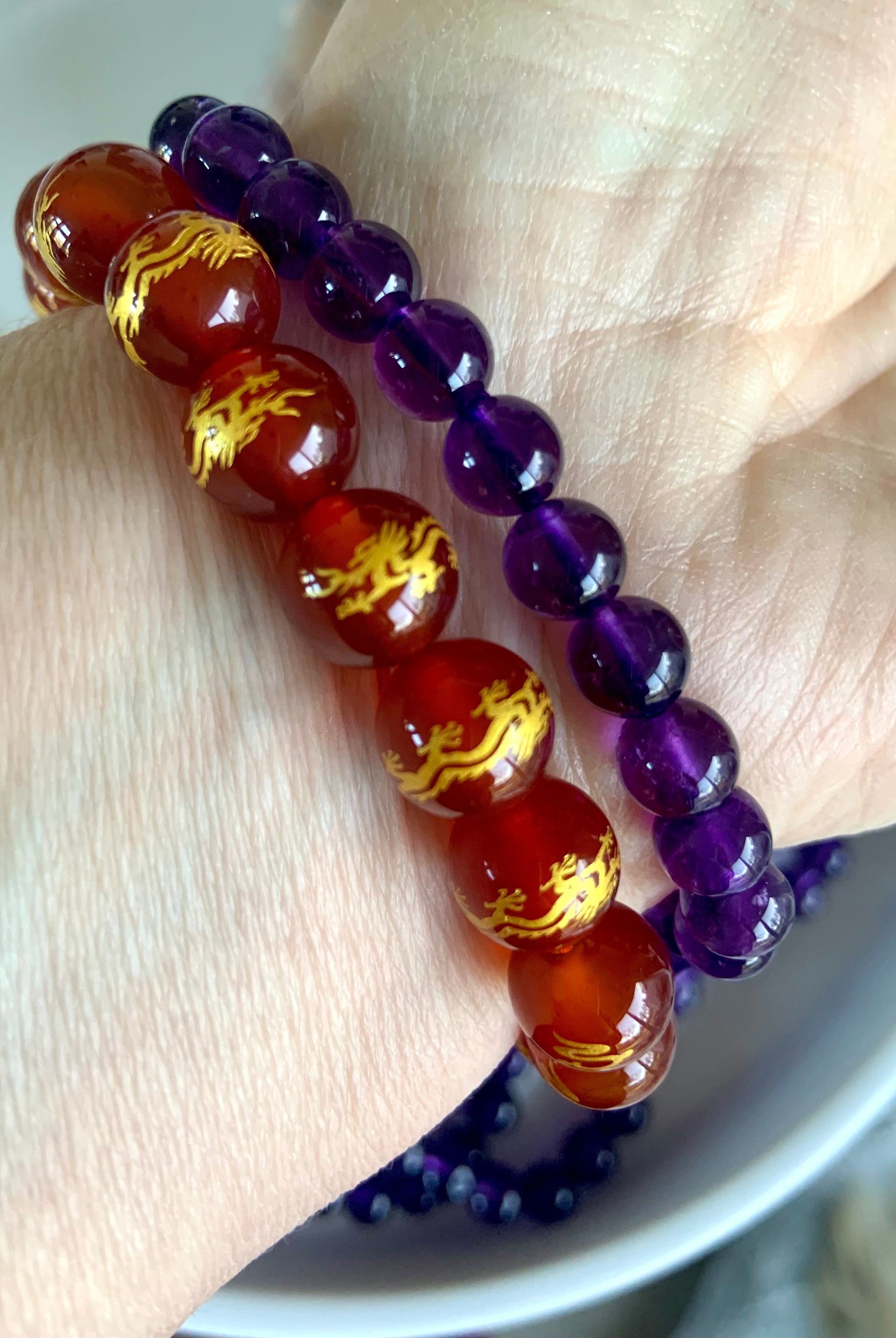 An amethyst bracelet worn with a carnelian bracelet with gold dragon beads