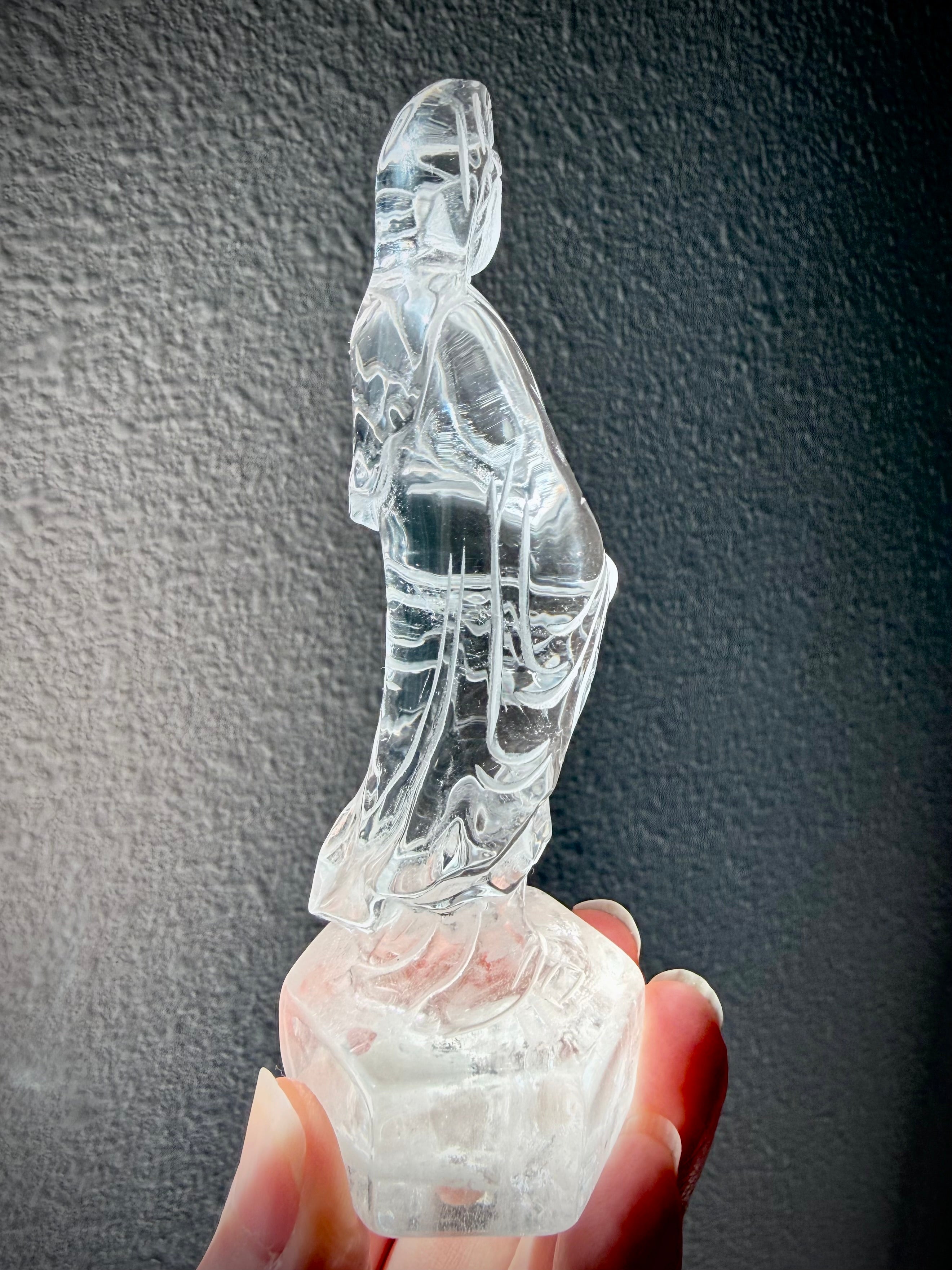 Side view of hand-carved Clear Quartz Quan Yin Goddess of Compassion statue with radiant transparency
