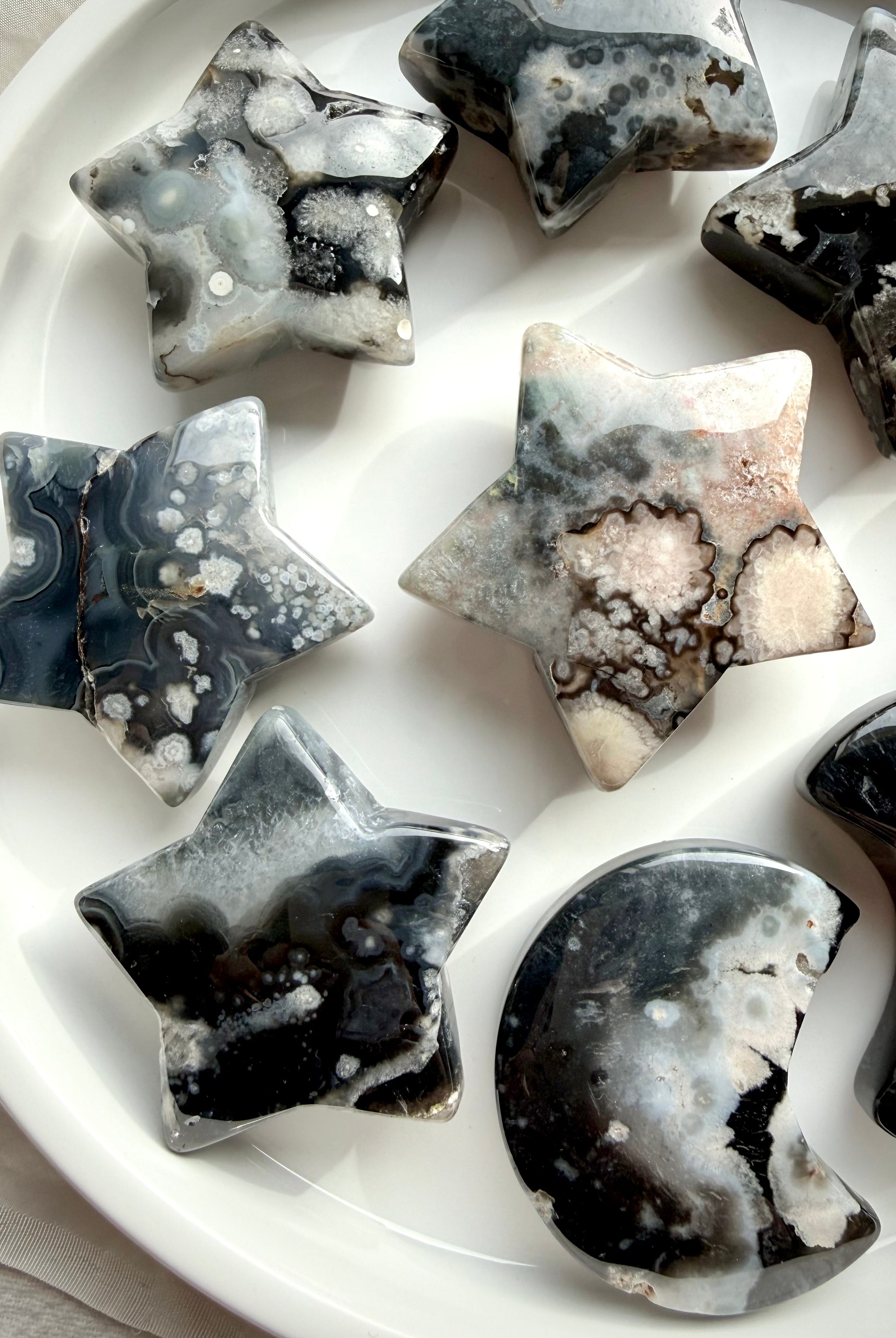 black flower agate moon and star carvings set on dish showing full assortment with natural floral plume patterns