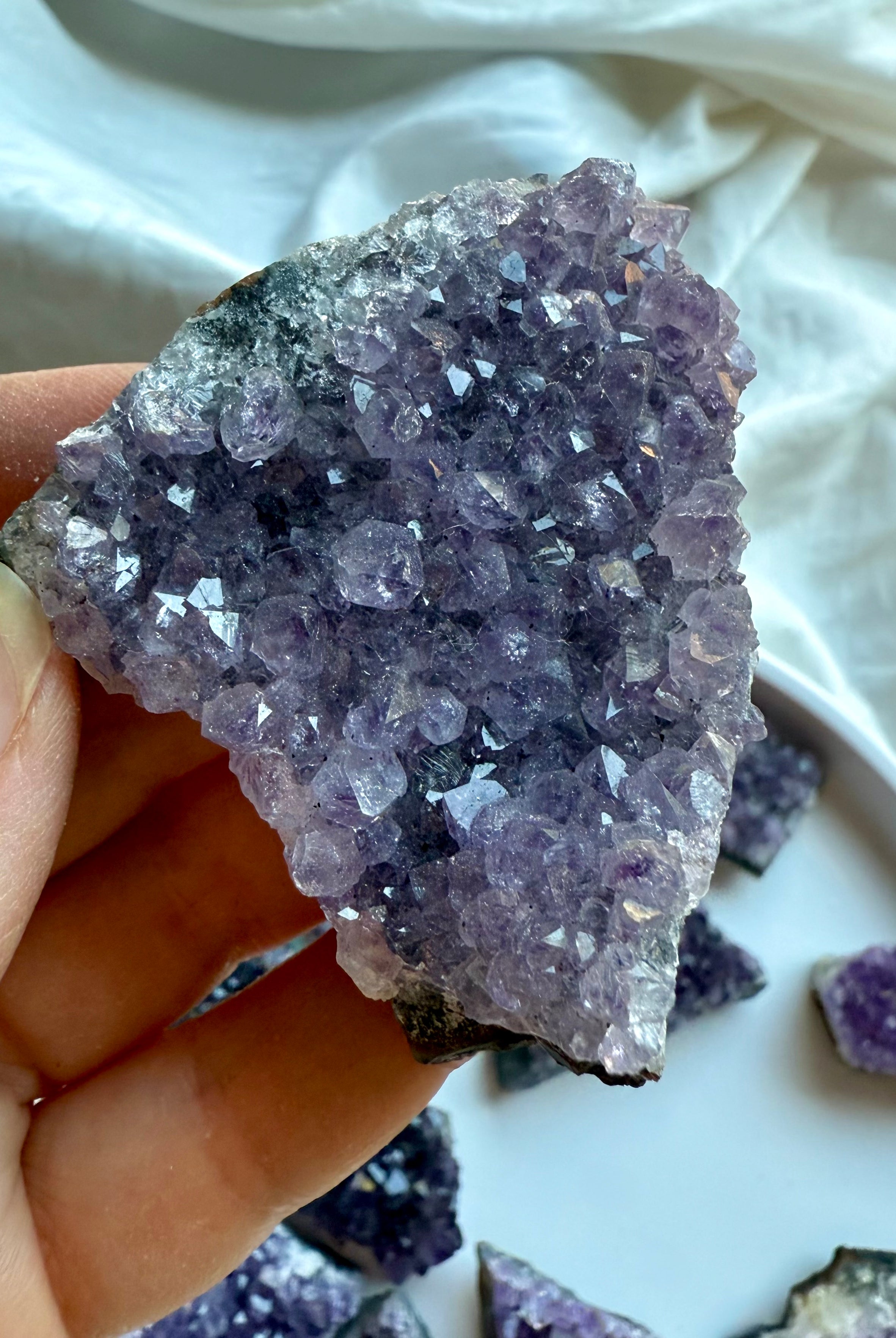 Purple amethyst geode cluster held in hand for size reference