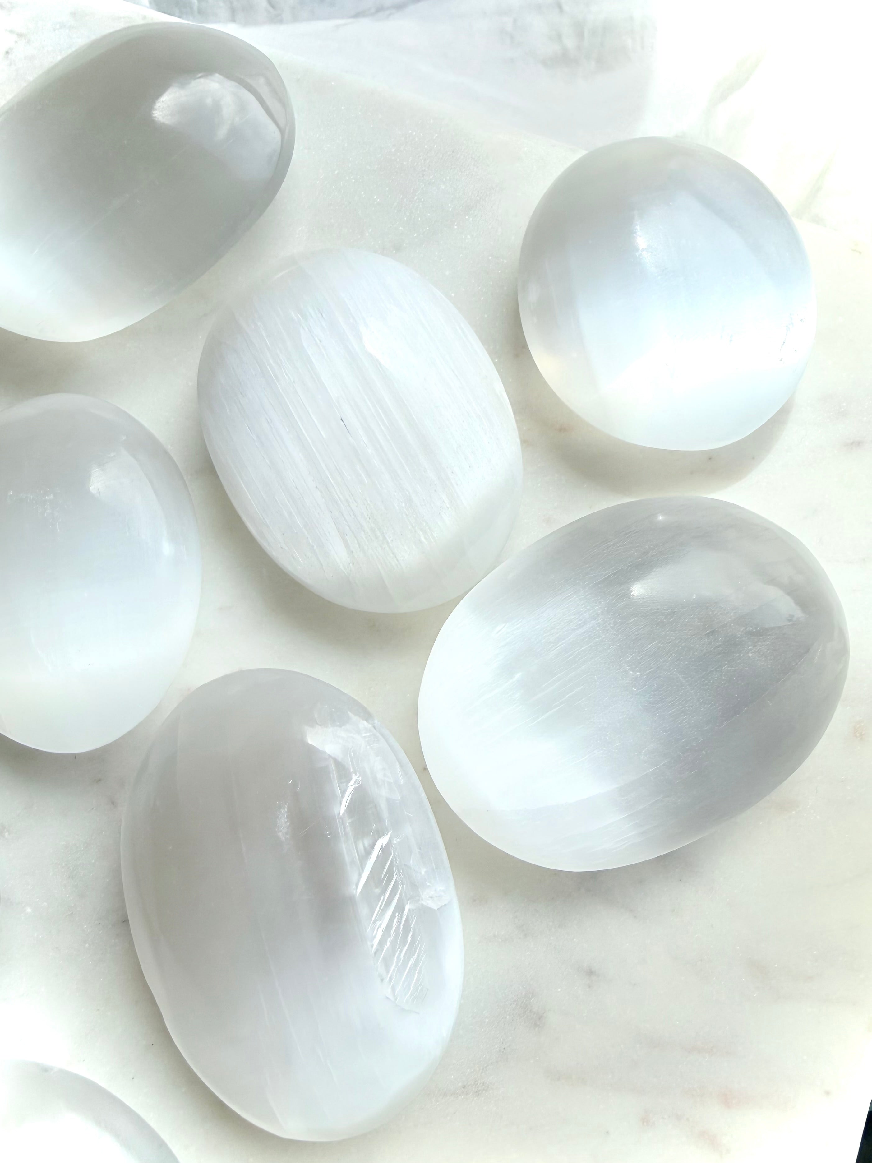 Group of polished Selenite palm stones with natural translucency, pearly glow, and smooth oval shapes for meditation