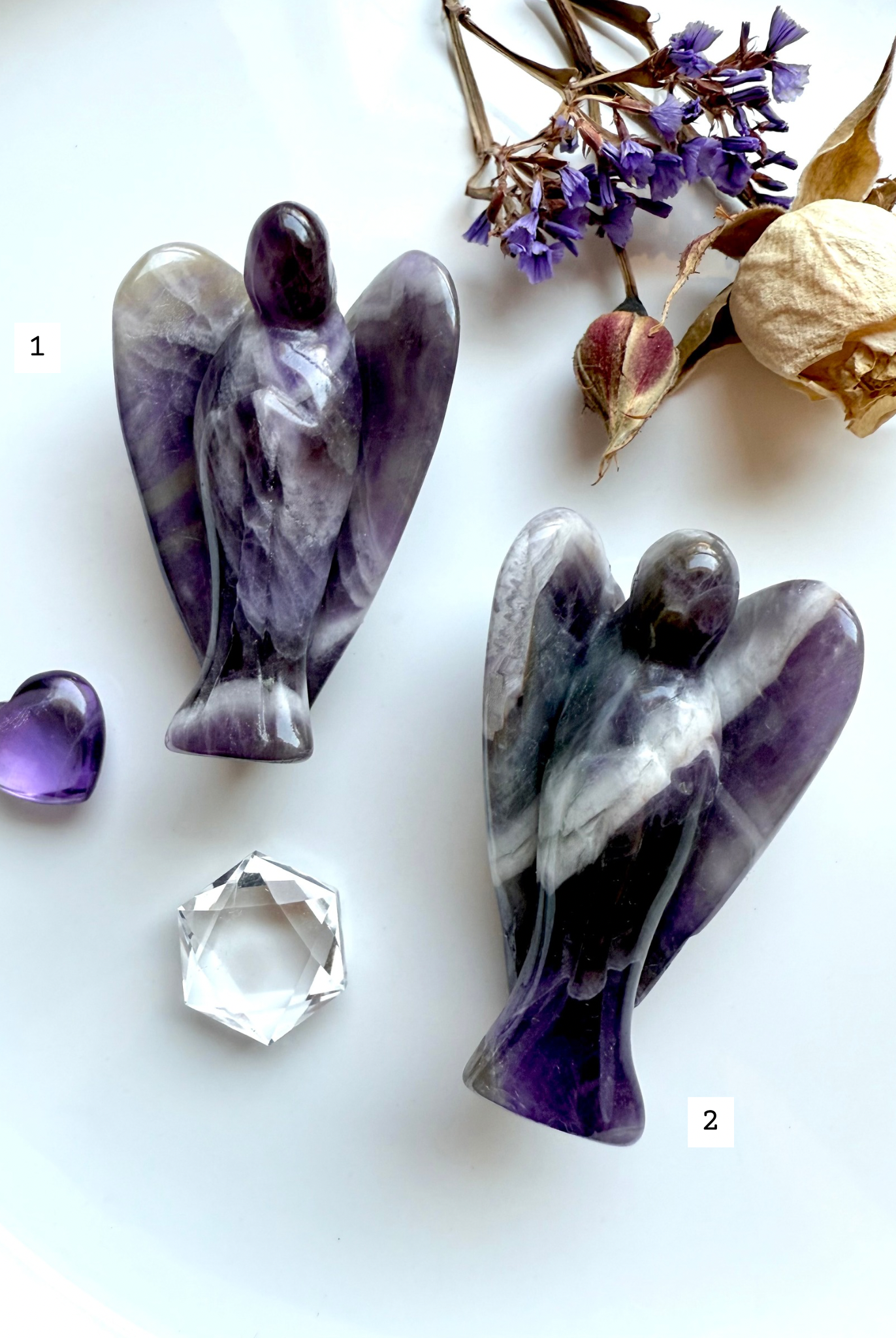 Choose-your-own Dream Amethyst angel carvings marked as #1 and #2, shown with dried flowers, purple Amethyst heart, and faceted quartz – ethically sourced from Zambia for peace and clarity