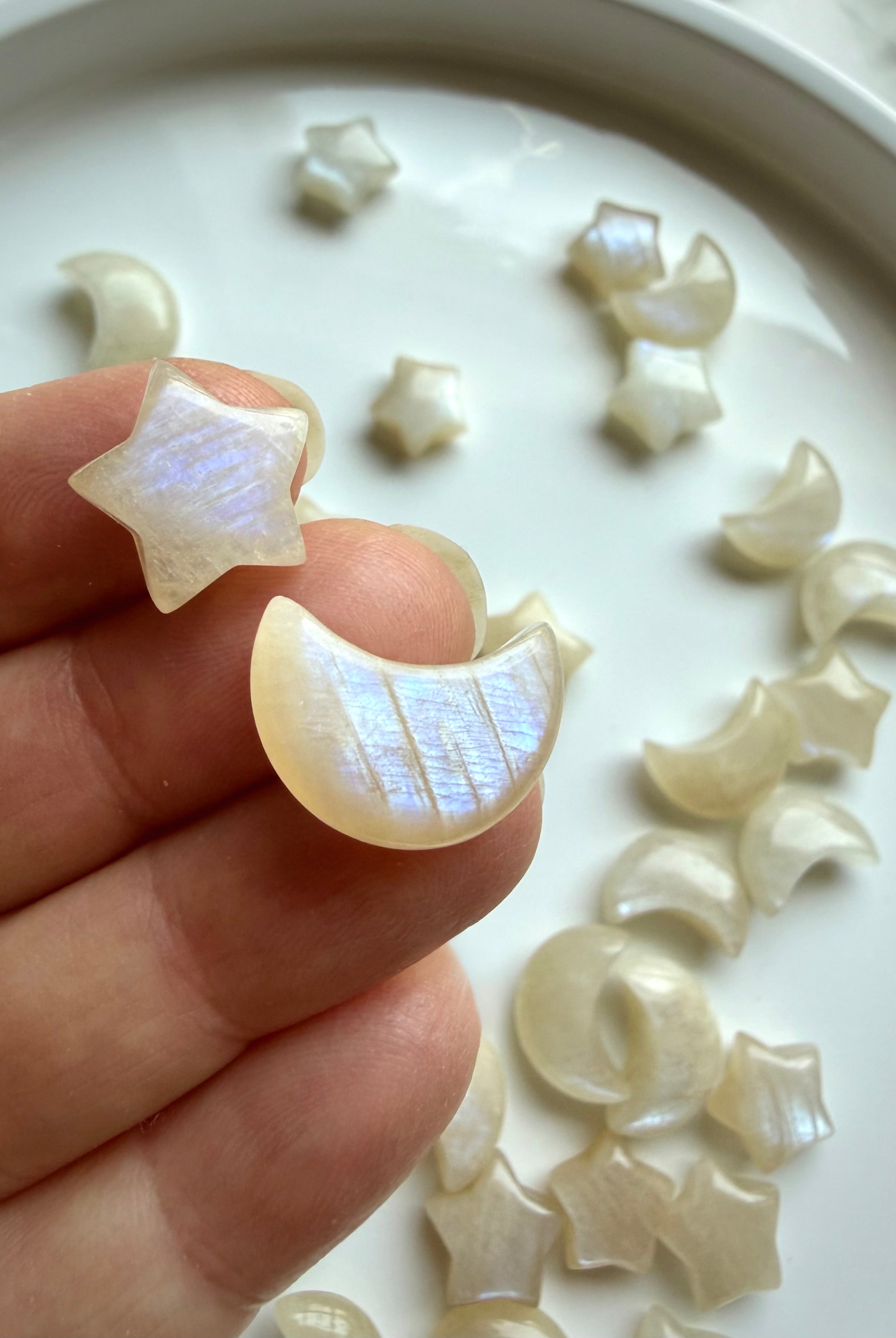 Mini Moonstone moon and star carvings displayed in hand showing luminous blue flash