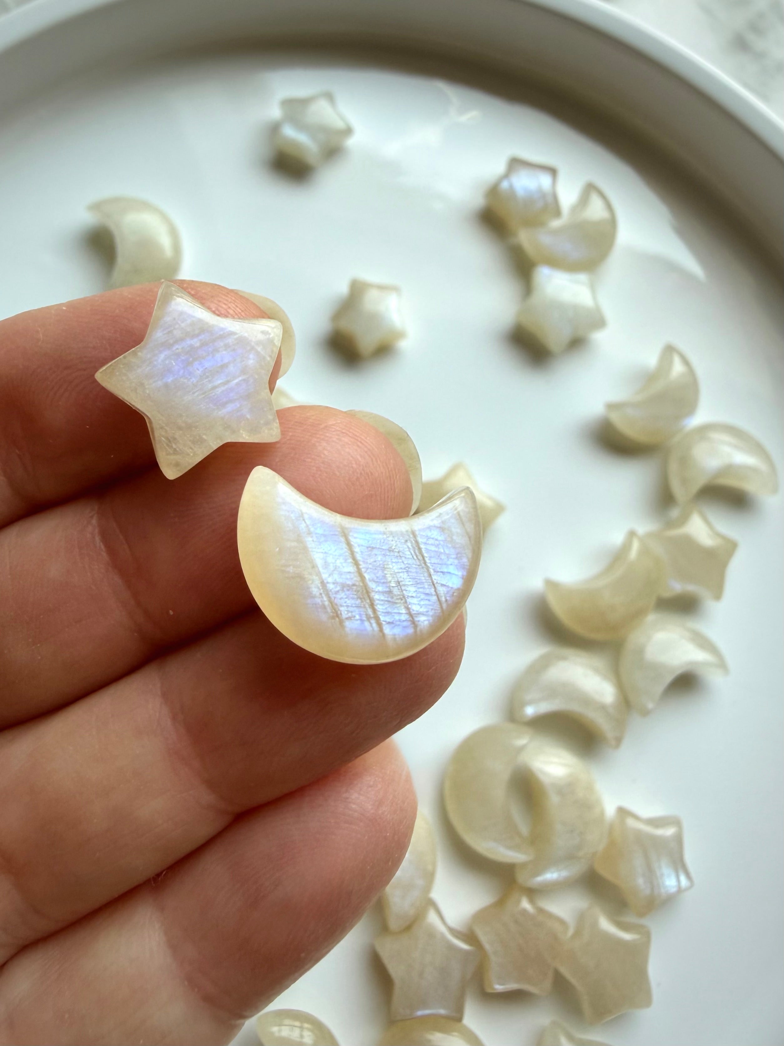Mini Moonstone moon and star carvings displayed in hand showing luminous blue flash
