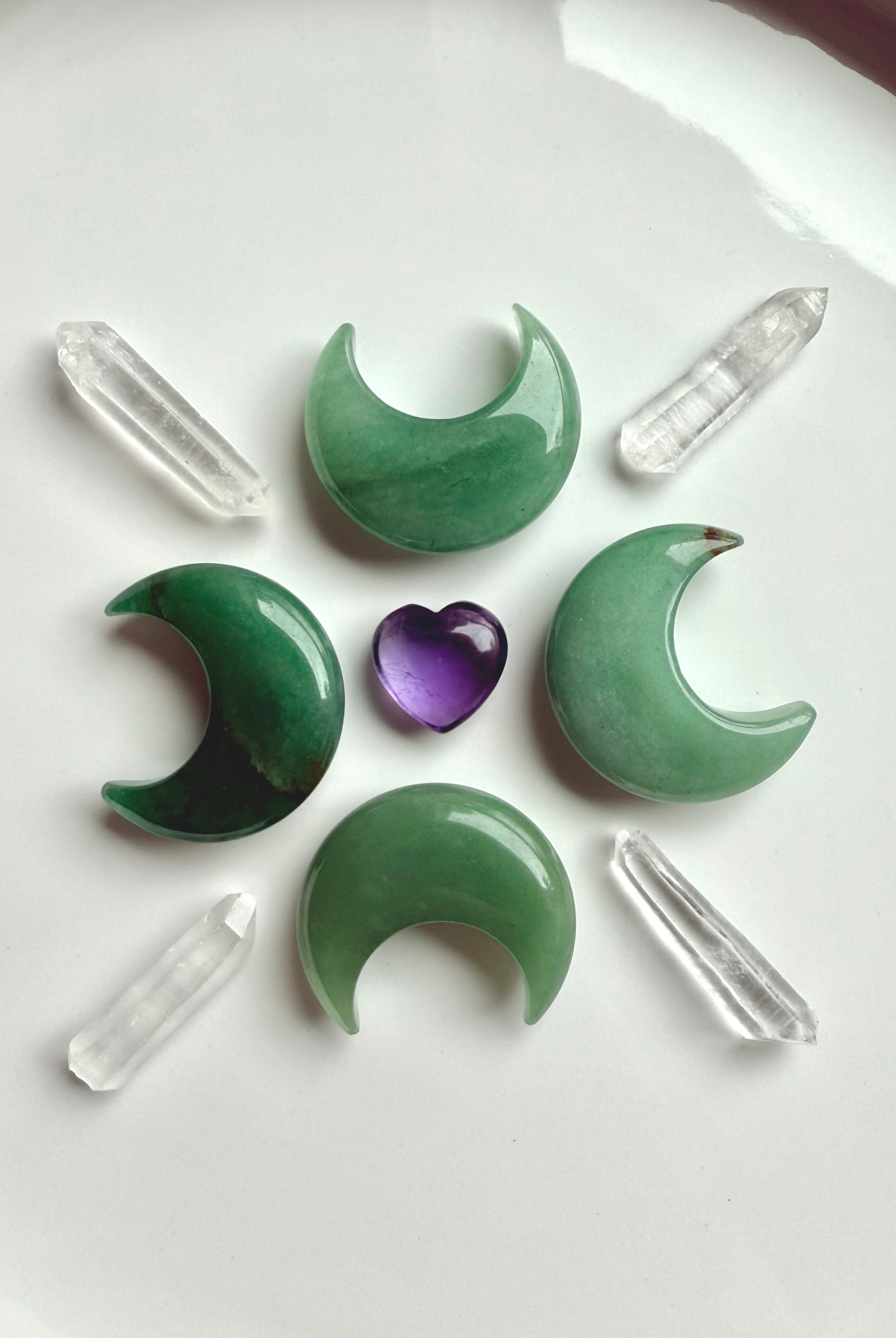 Crystal grid with Green Aventurine moons, clear quartz points, and amethyst heart center, crystals for healing and abundance rituals