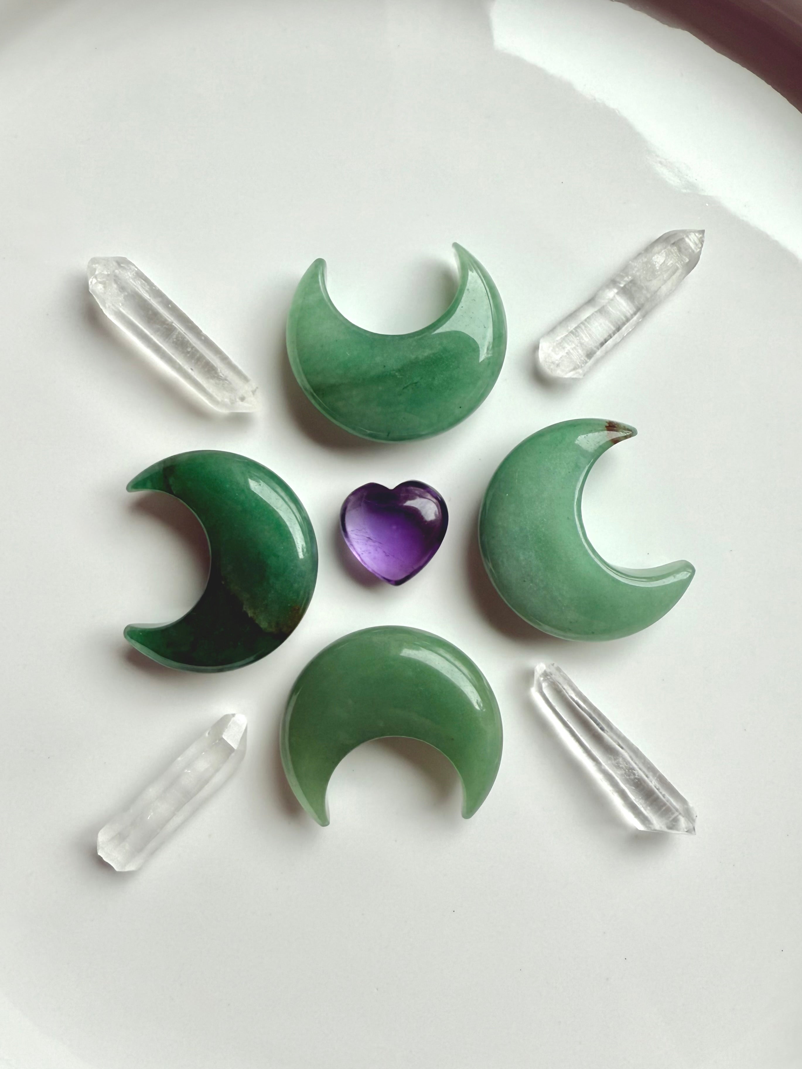 Crystal grid with Green Aventurine moons, clear quartz points, and amethyst heart center, crystals for healing and abundance rituals