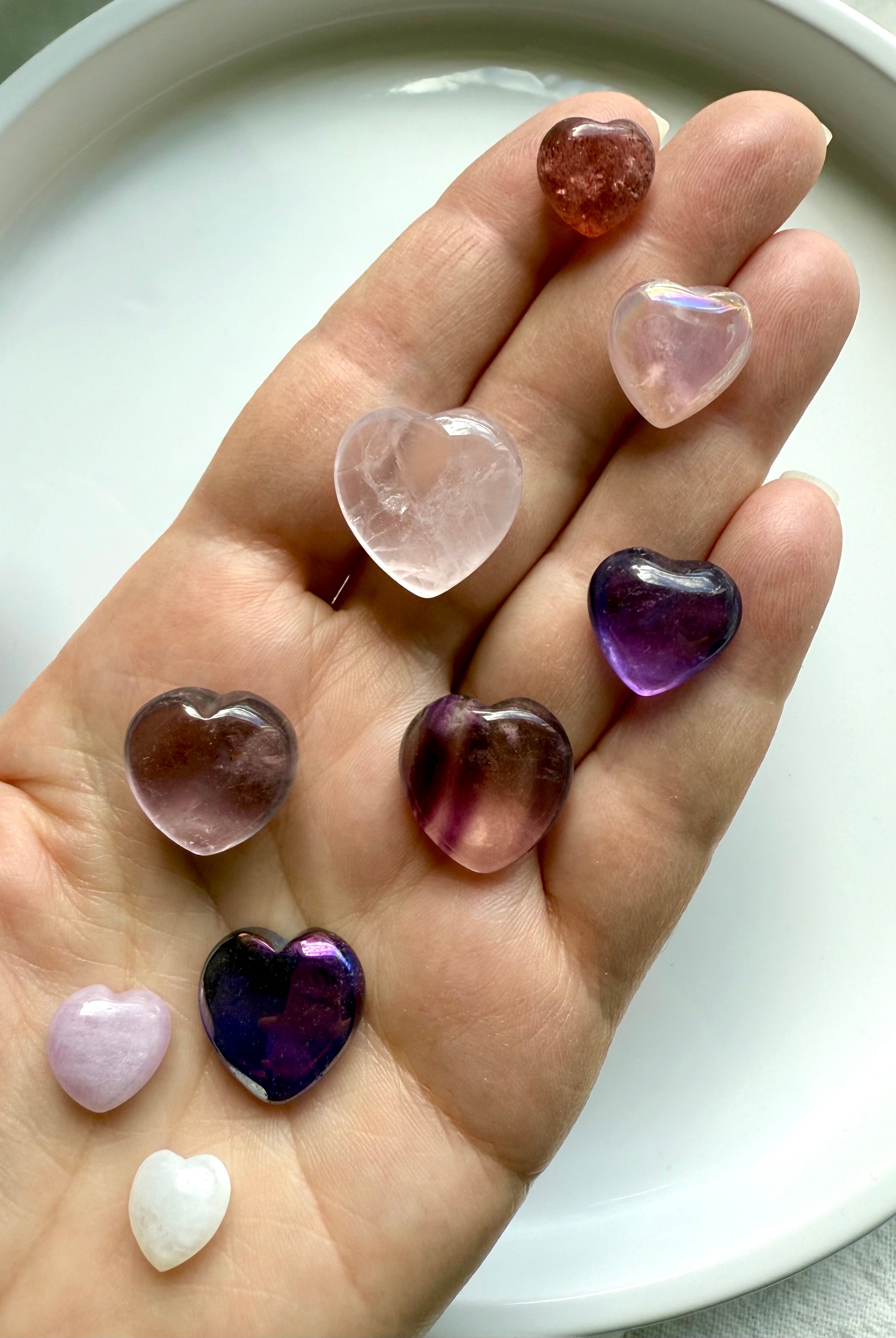 Pink and purple mini crystal hearts displayed in hand, premium gemstone carvings for love and healing.