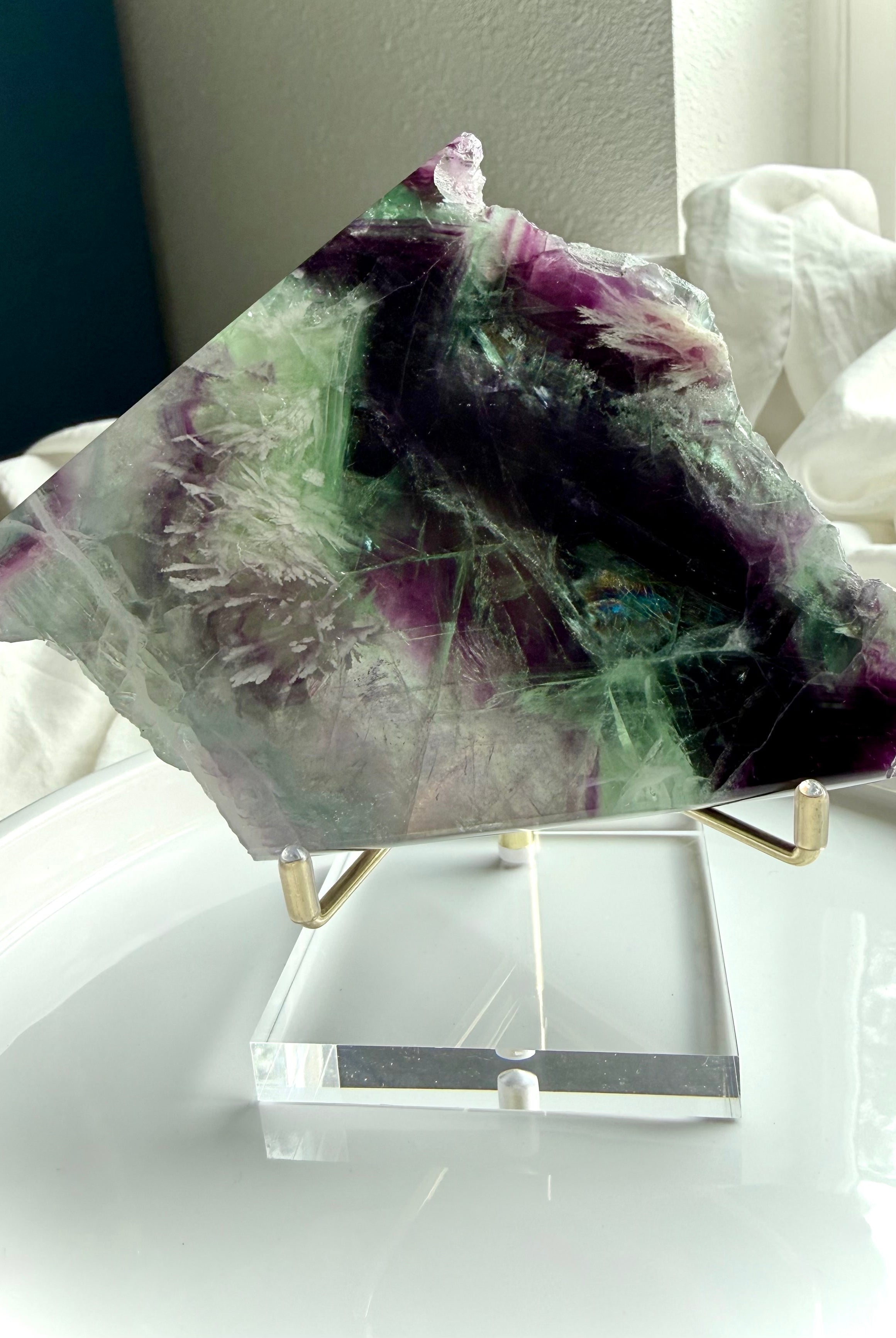 One of a kind green and purple fluorite slab shown on an elegant display stand