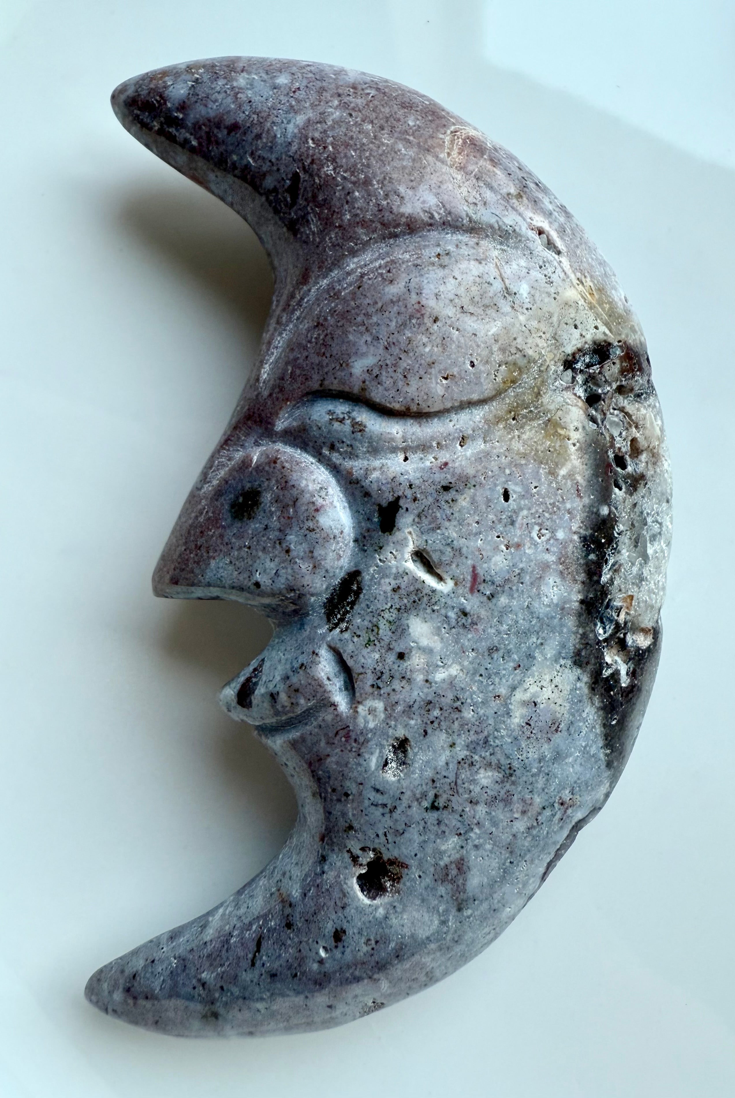 Polished Ocean Jasper crescent moon crystal carving in purple hues shown on white.