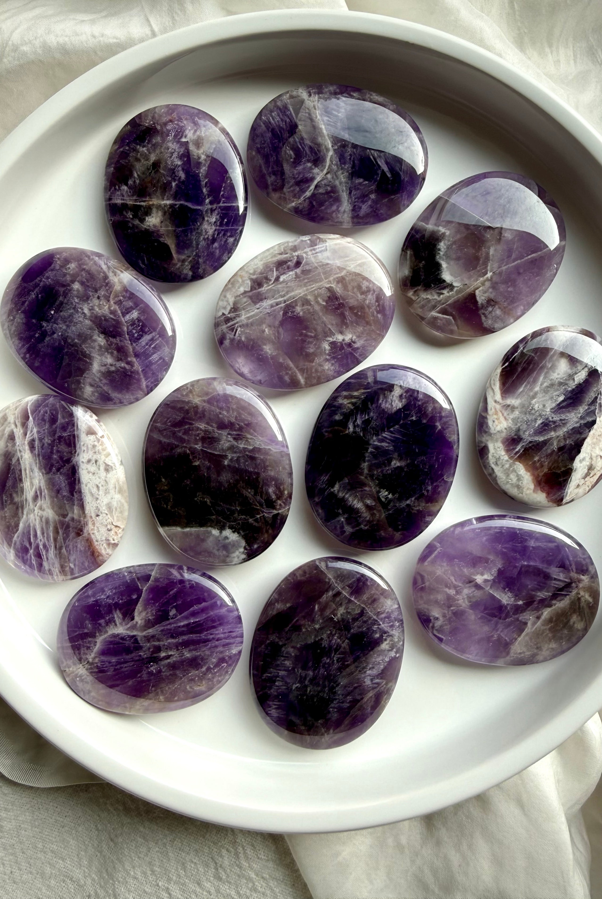 Dream amethyst flat palm stones showing natural variation in purple, lavender, white, and smoky banding, polished pocket crystals for calm and restful sleep