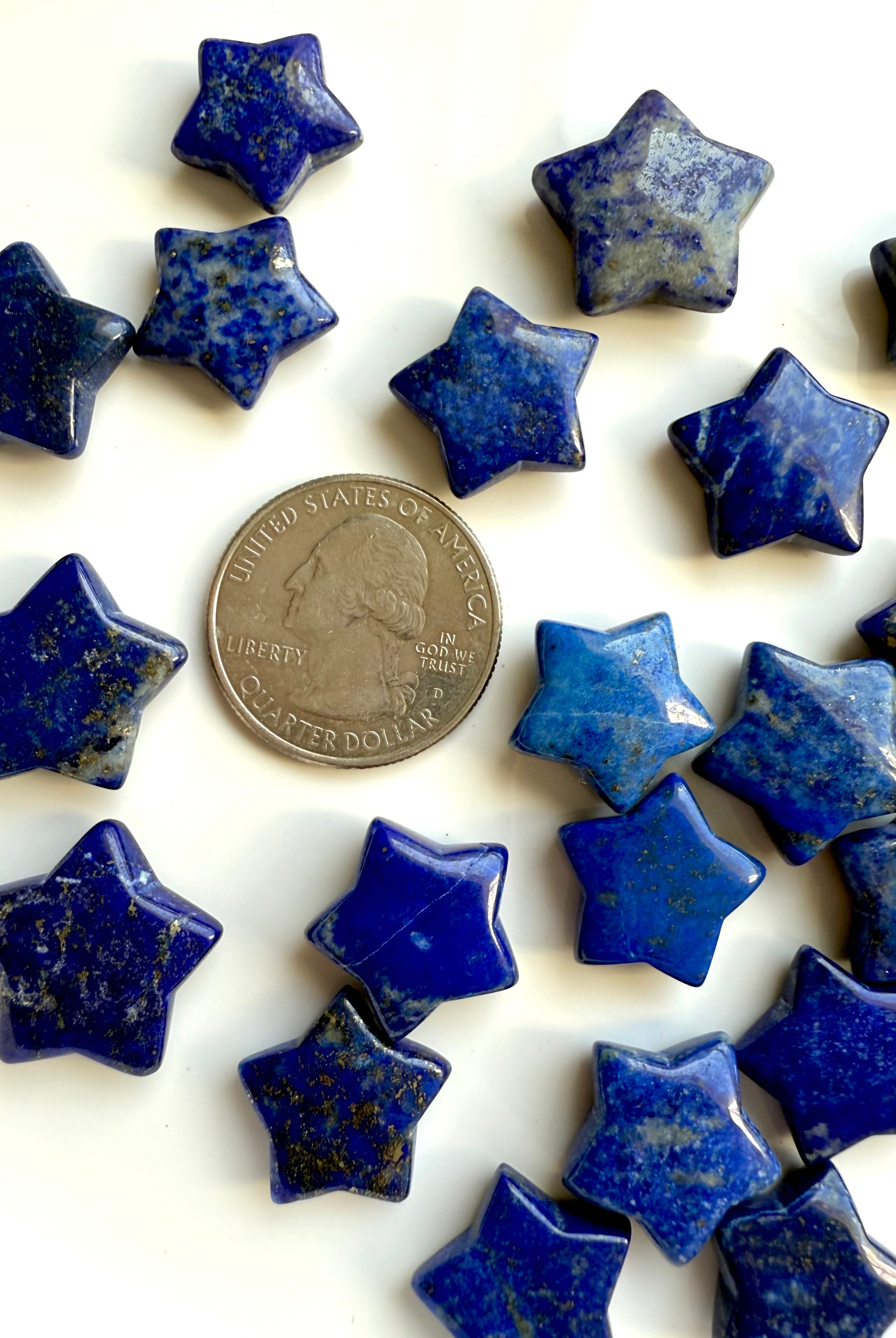Close up of Mini Lapis Lazuli star carvings next to a US quarter for size comparison