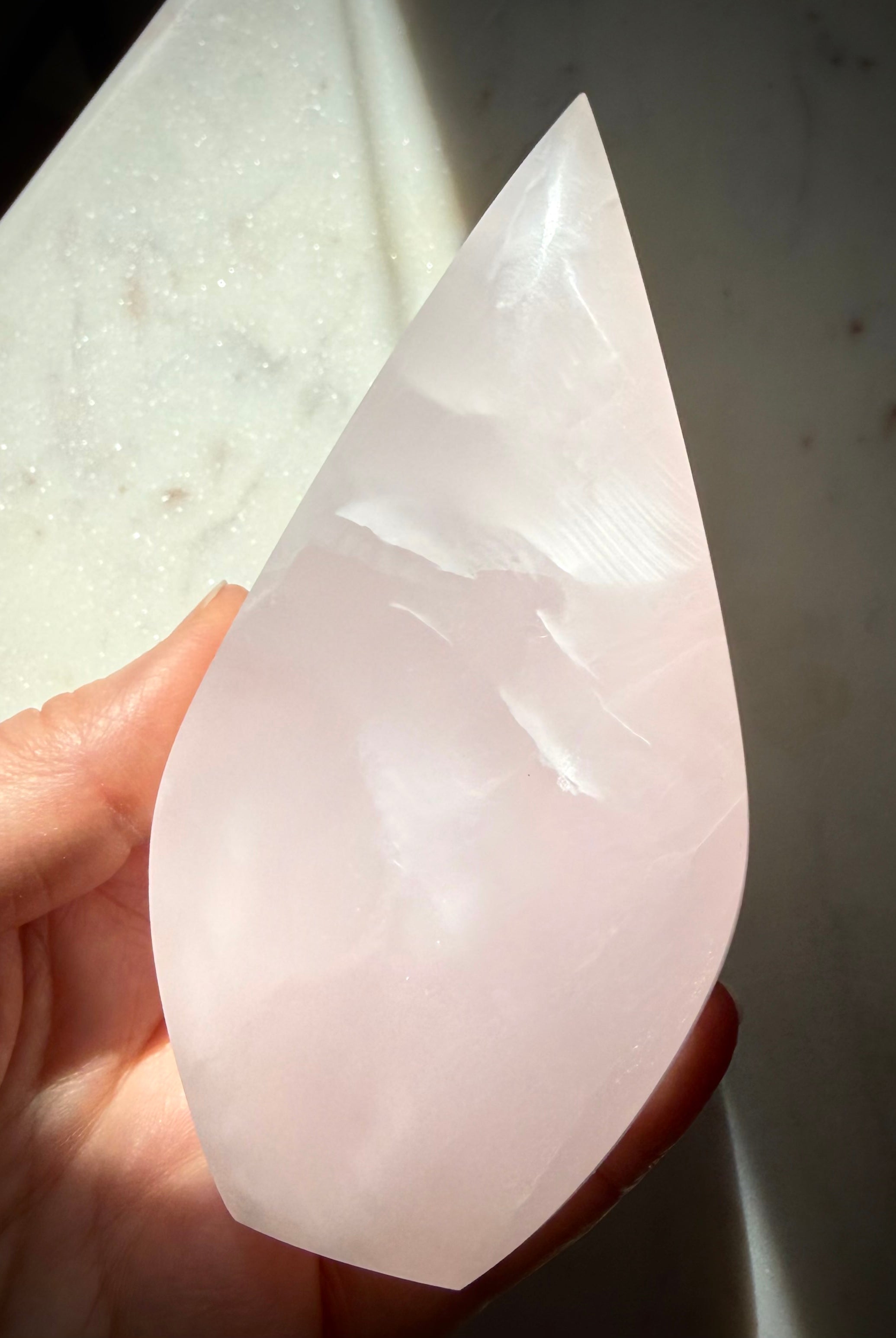 Polished Mangano Calcite flame held in hand showing graceful shape, natural beauty and emotional healing energy