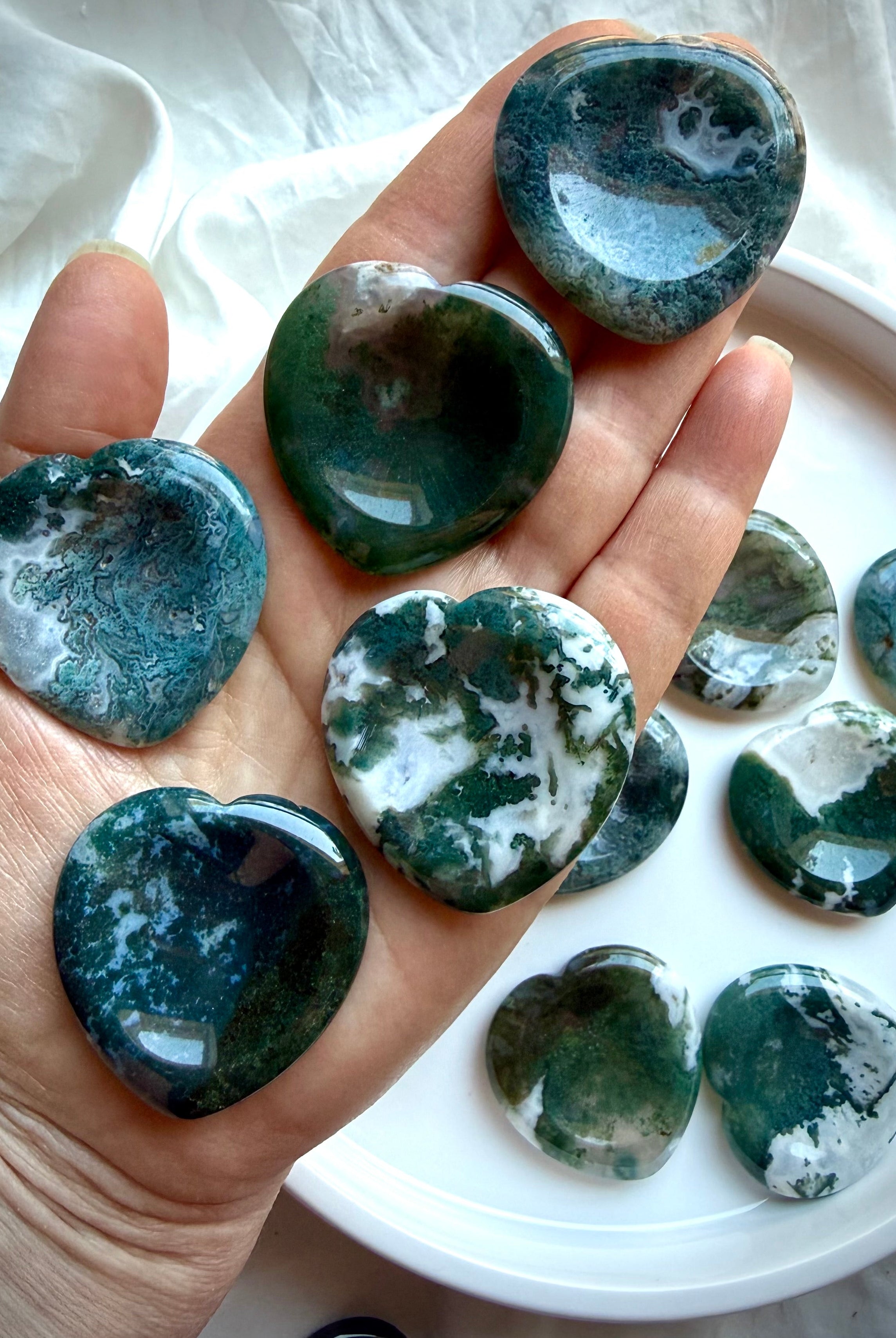 Moss Agate heart worry stone shown on hand with translucent quartz and lush green moss inclusions
