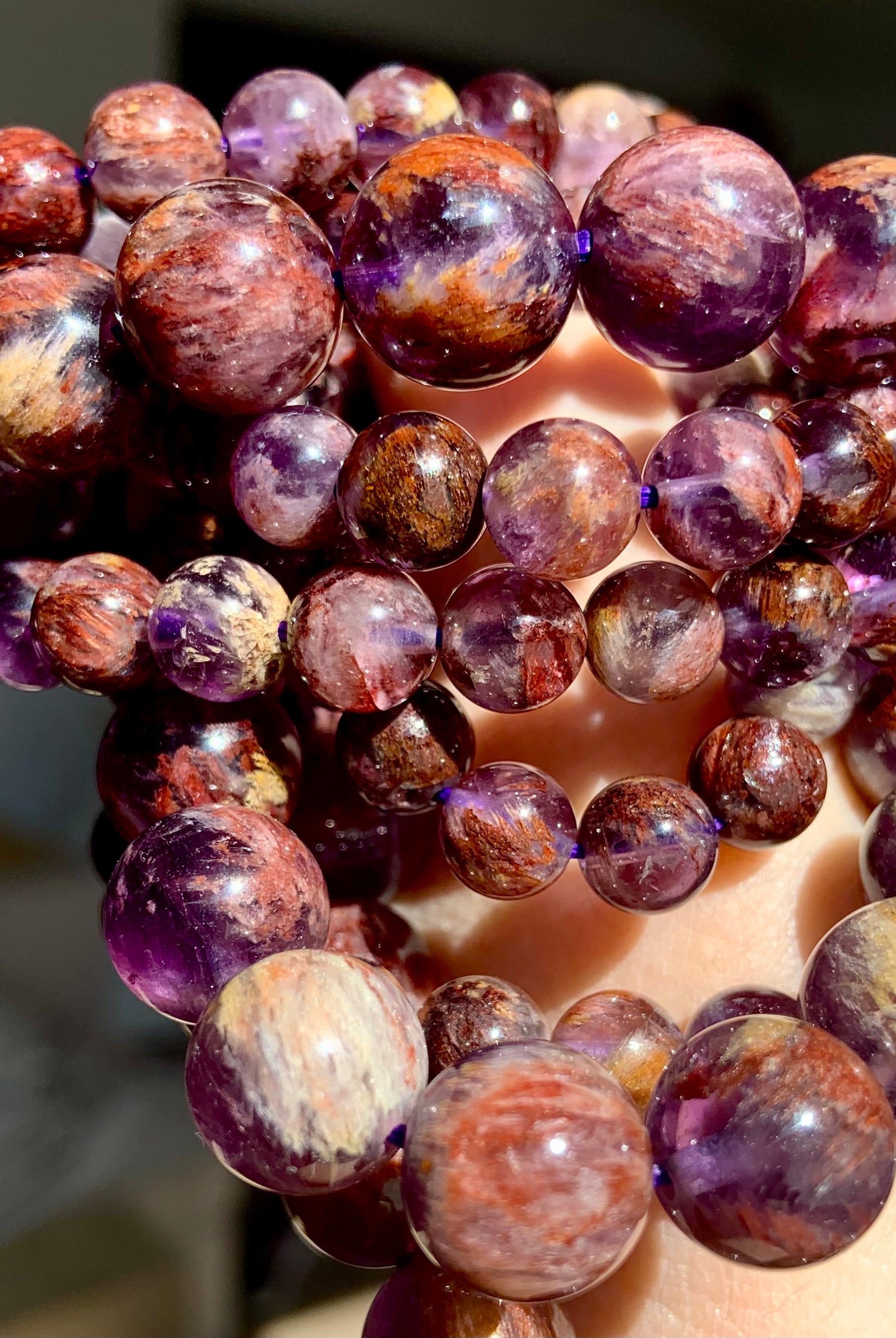 Super 7 Amethyst crystal bracelet stacked on wrist with natural purple and reddish mineral inclusions