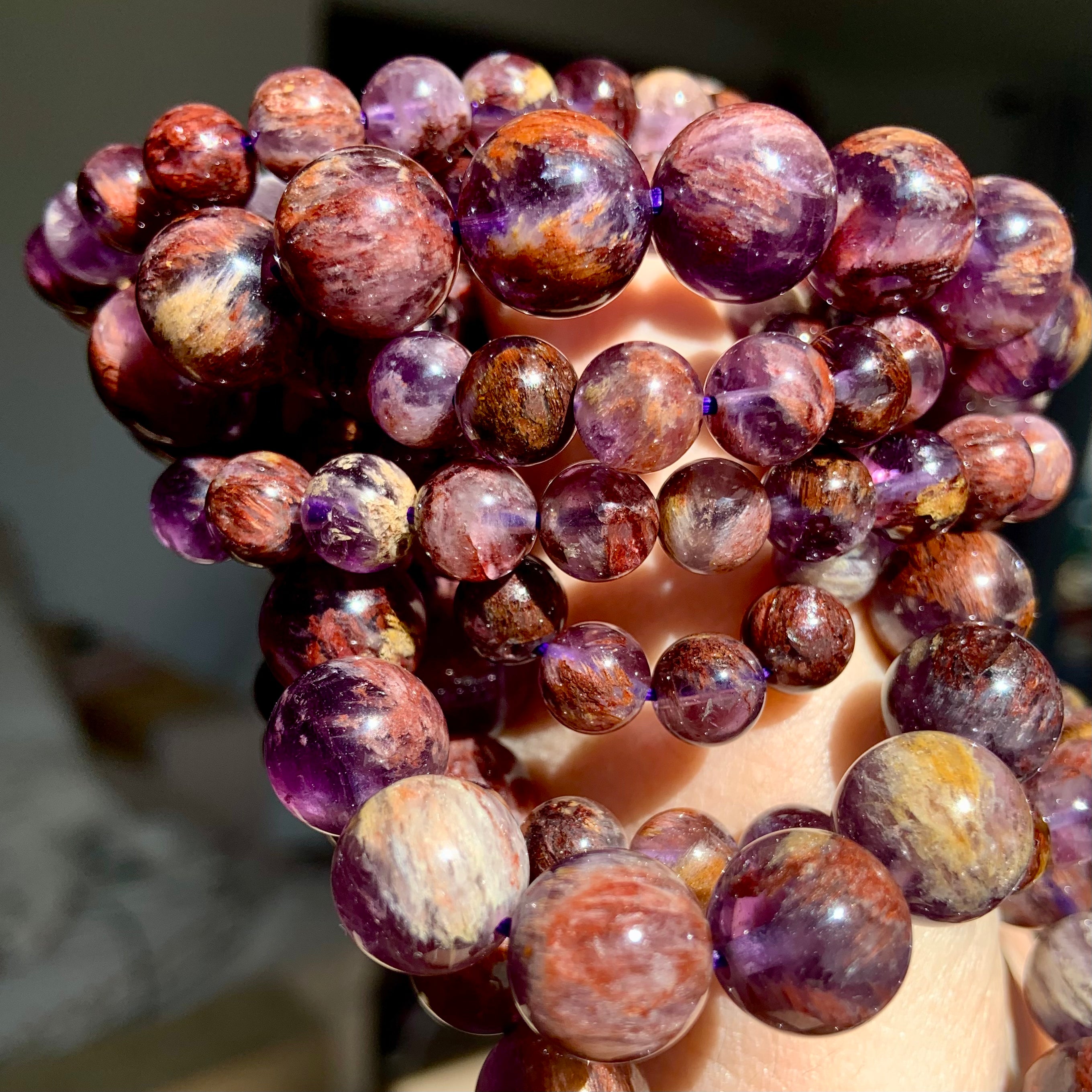 Super 7 Amethyst crystal bracelet stacked on wrist with natural purple and reddish mineral inclusions