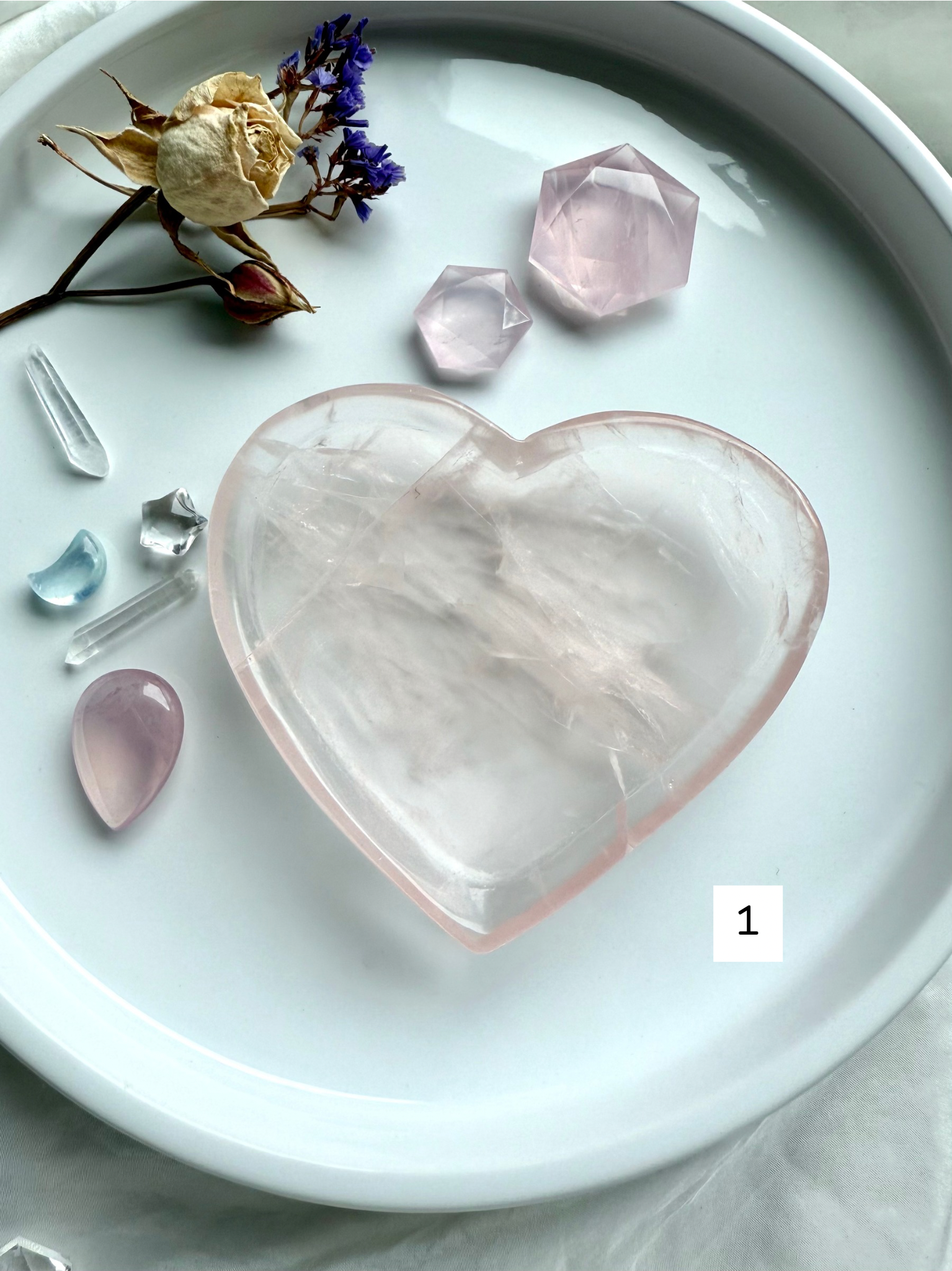 Rose Quartz heart bowl held in hand, showing its translucent pink clarity and etched inner inclusions for heart-healing energy.