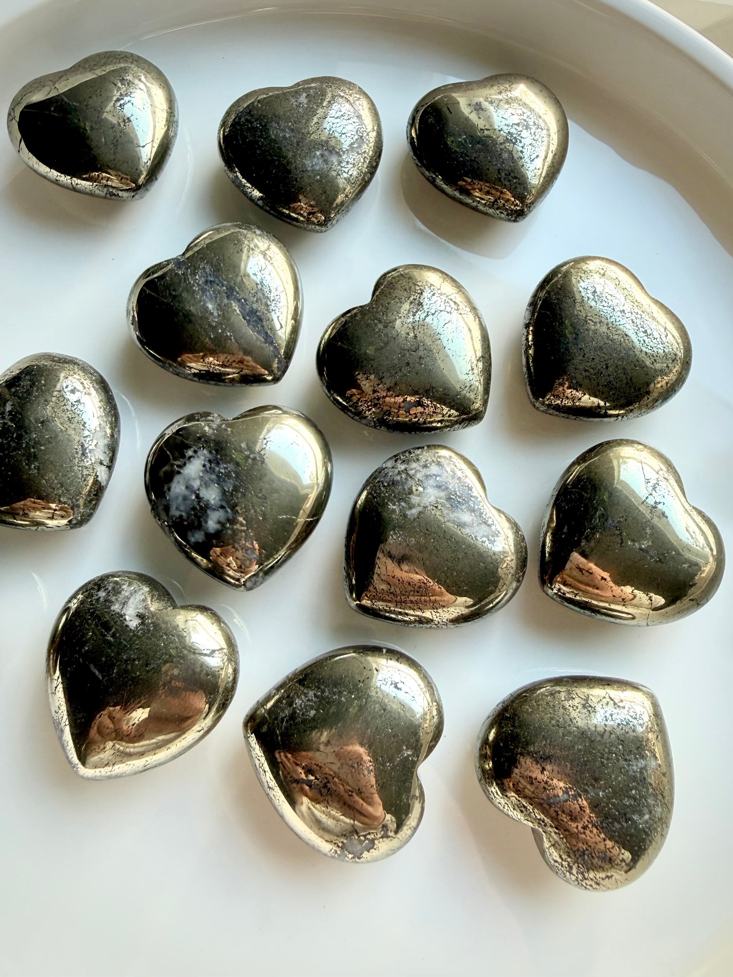 Pyrite heart crystals arranged on white tray, symbolic stones for protection, motivation, and success