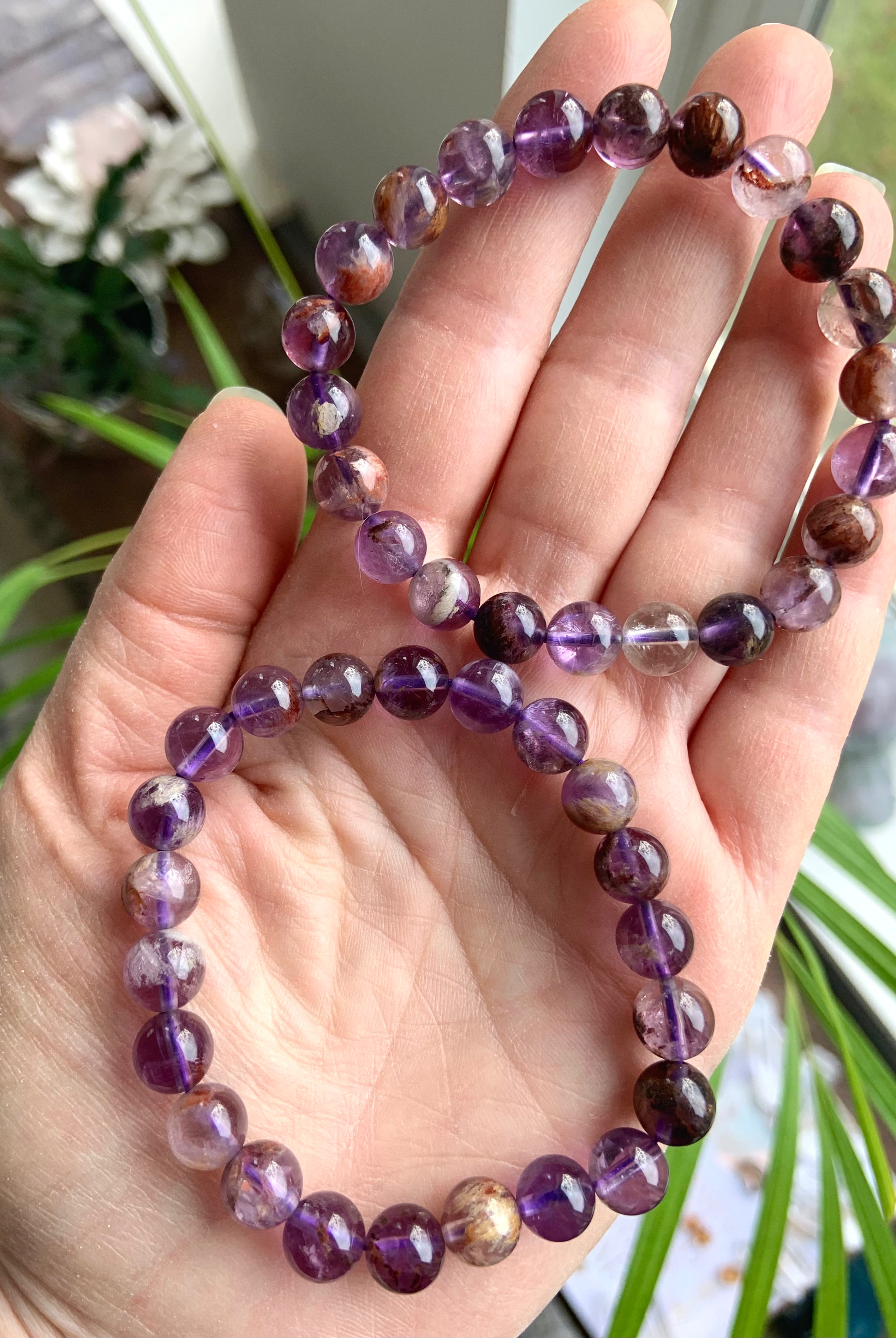 Two Super 7 Amethyst crystal bracelets worn on hand showing natural purple and mineral inclusions