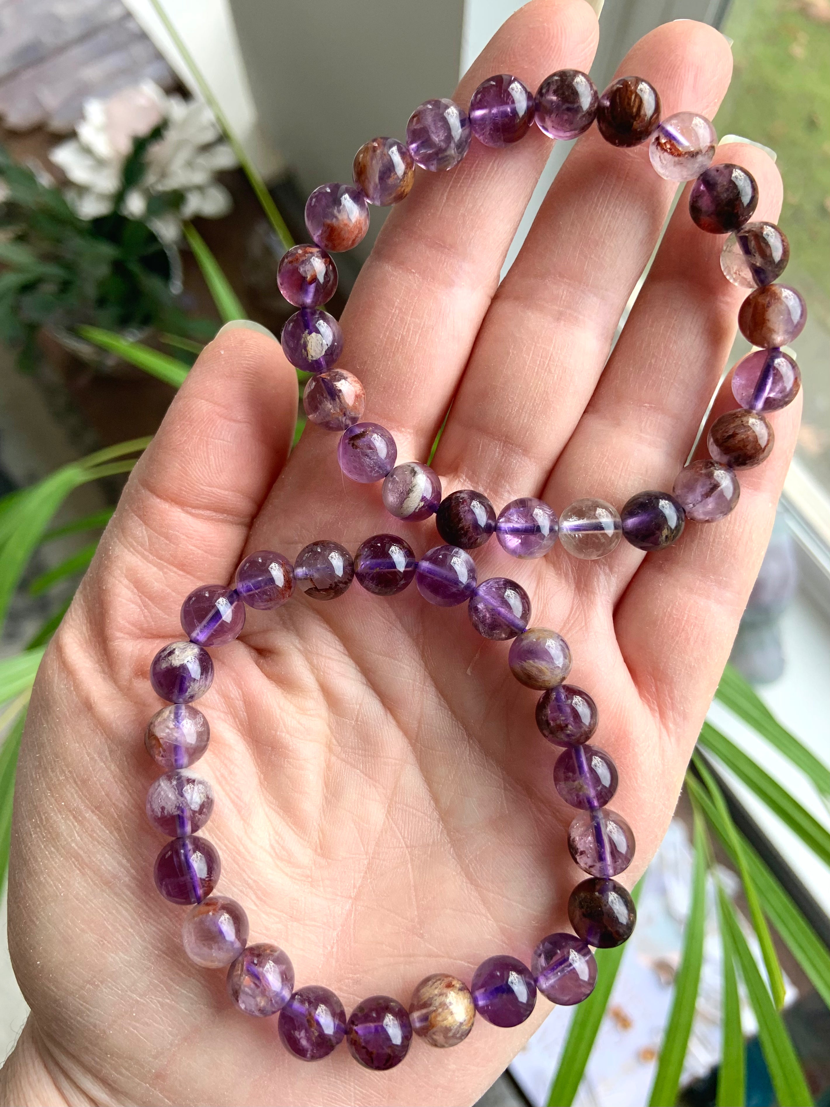 Two Super 7 Amethyst crystal bracelets worn on hand showing natural purple and mineral inclusions