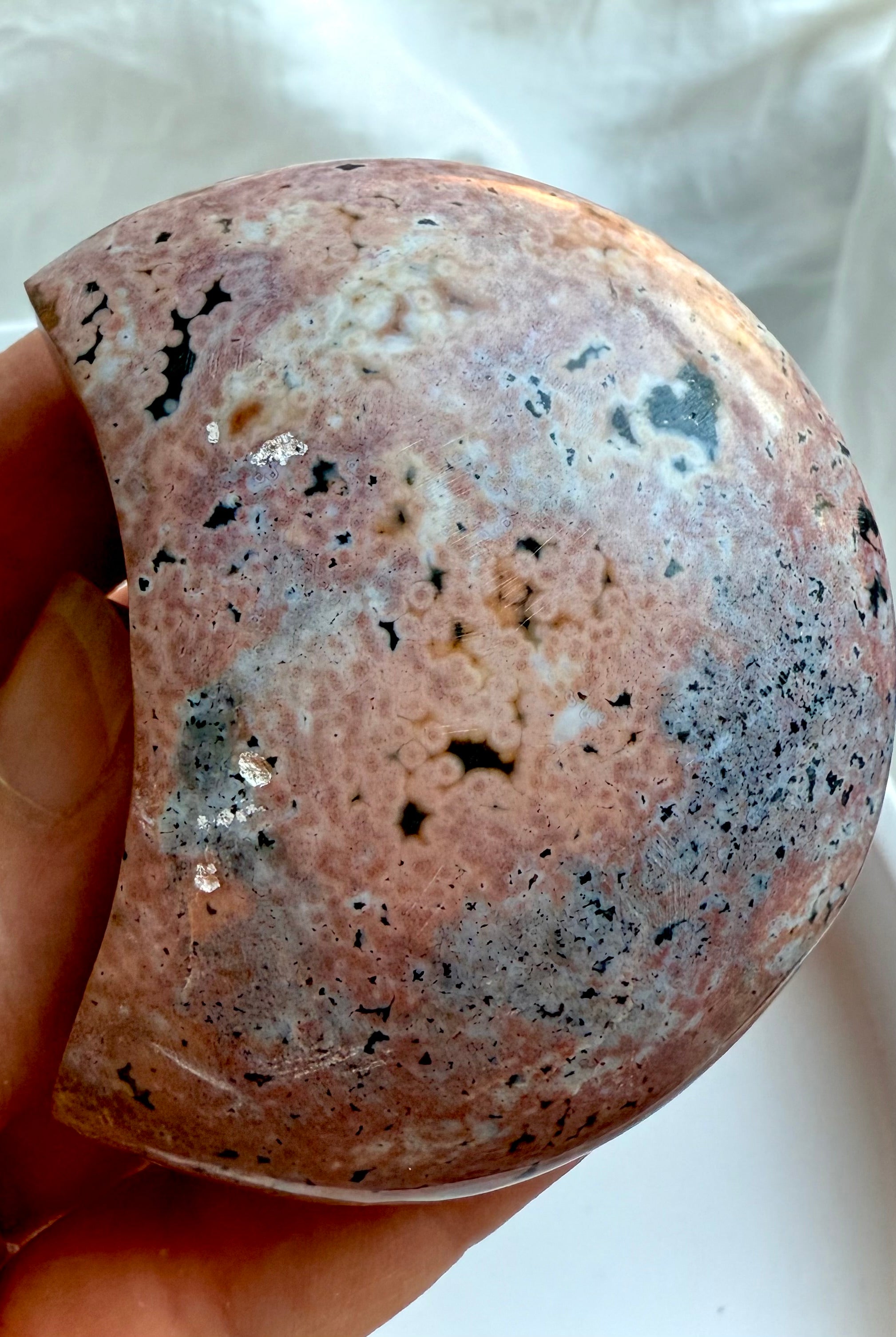 Ocean Jasper crescent moon crystal displaying soft pink, cream, and black orbicular patterns for calming energy