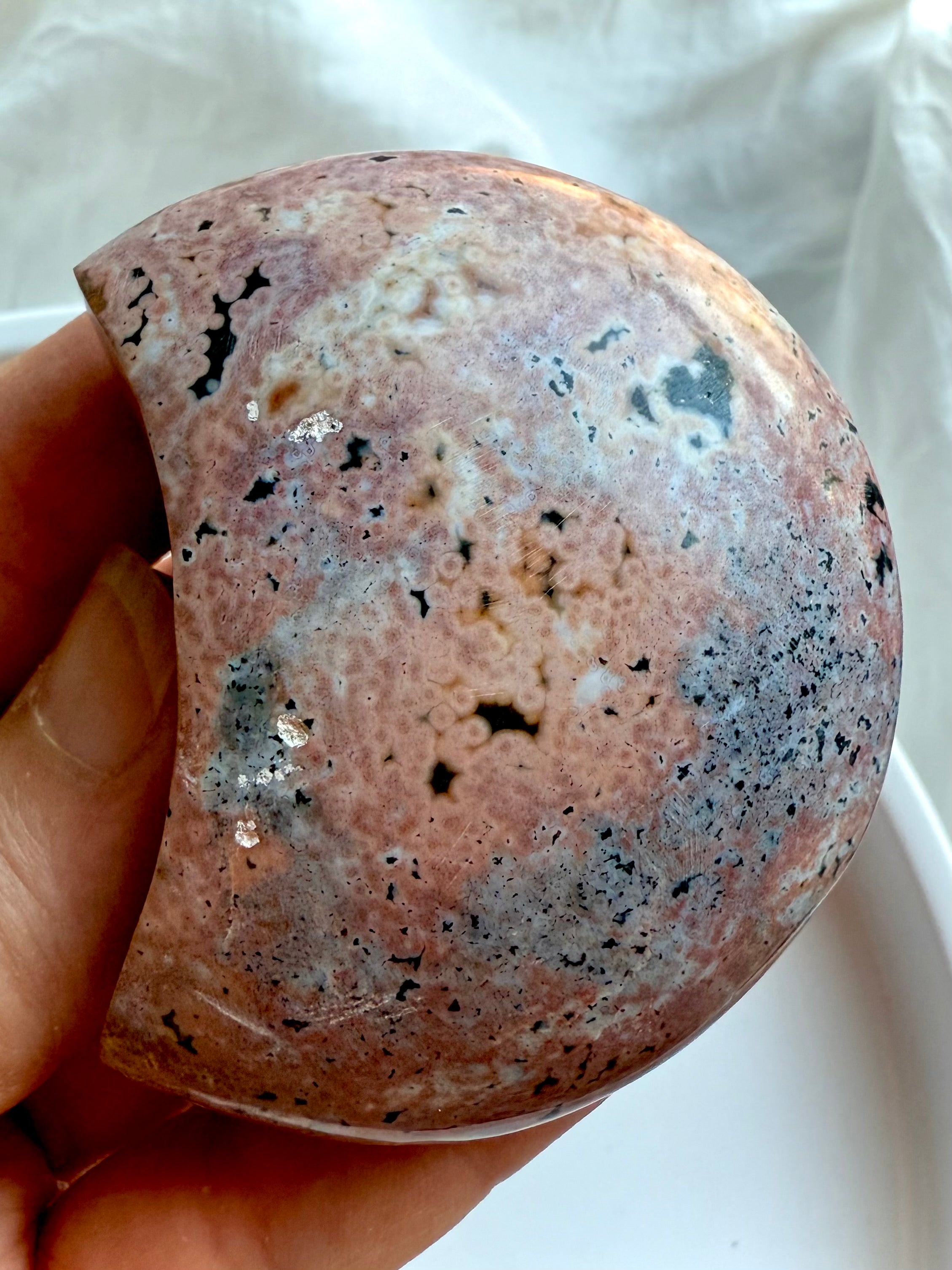 Ocean Jasper crescent moon crystal displaying soft pink, cream, and black orbicular patterns for calming energy