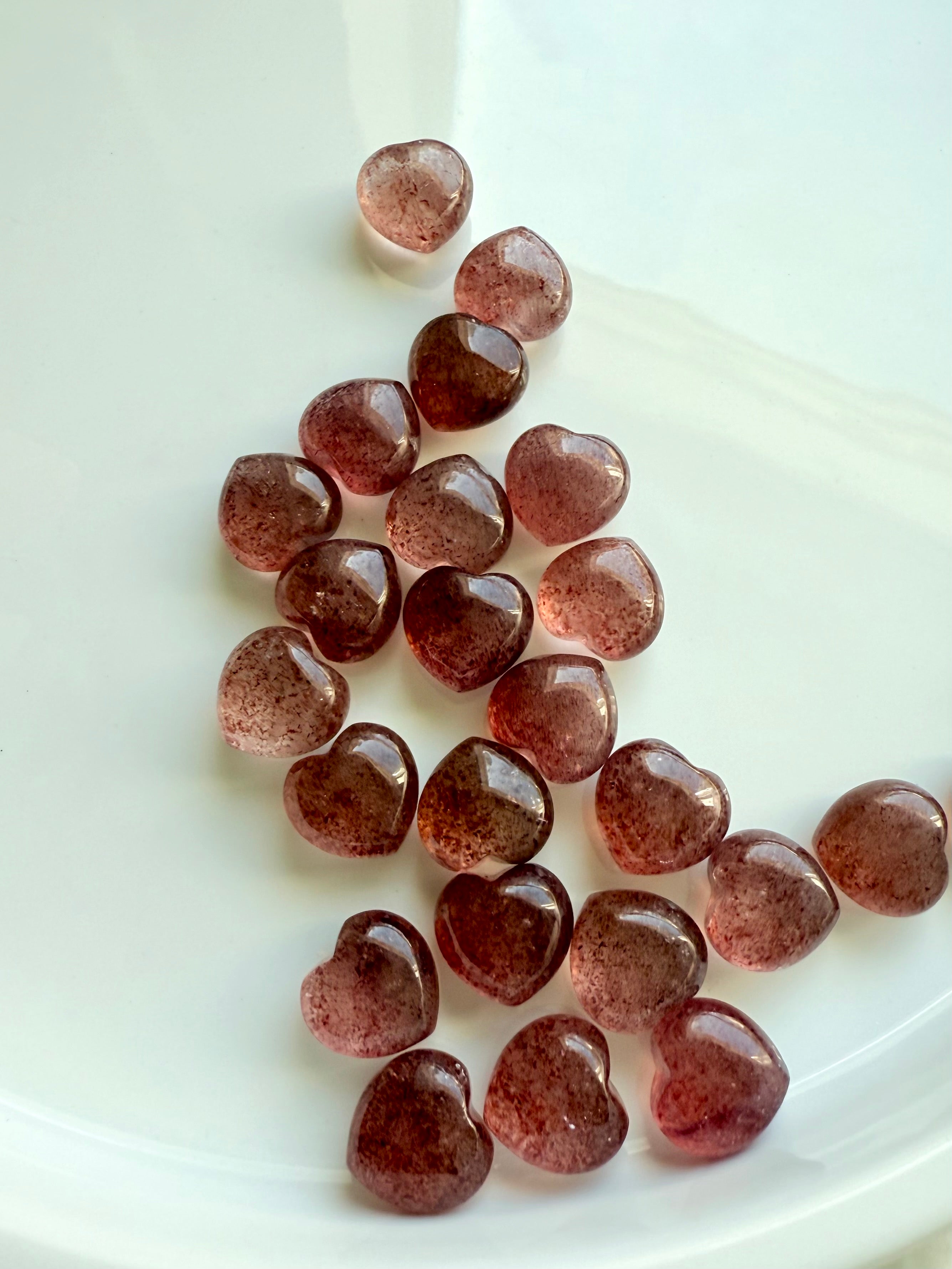 Array of Strawberry Quartz mini hearts on a white background — tanzberry quartz carvings for heart chakra healing and self-love.