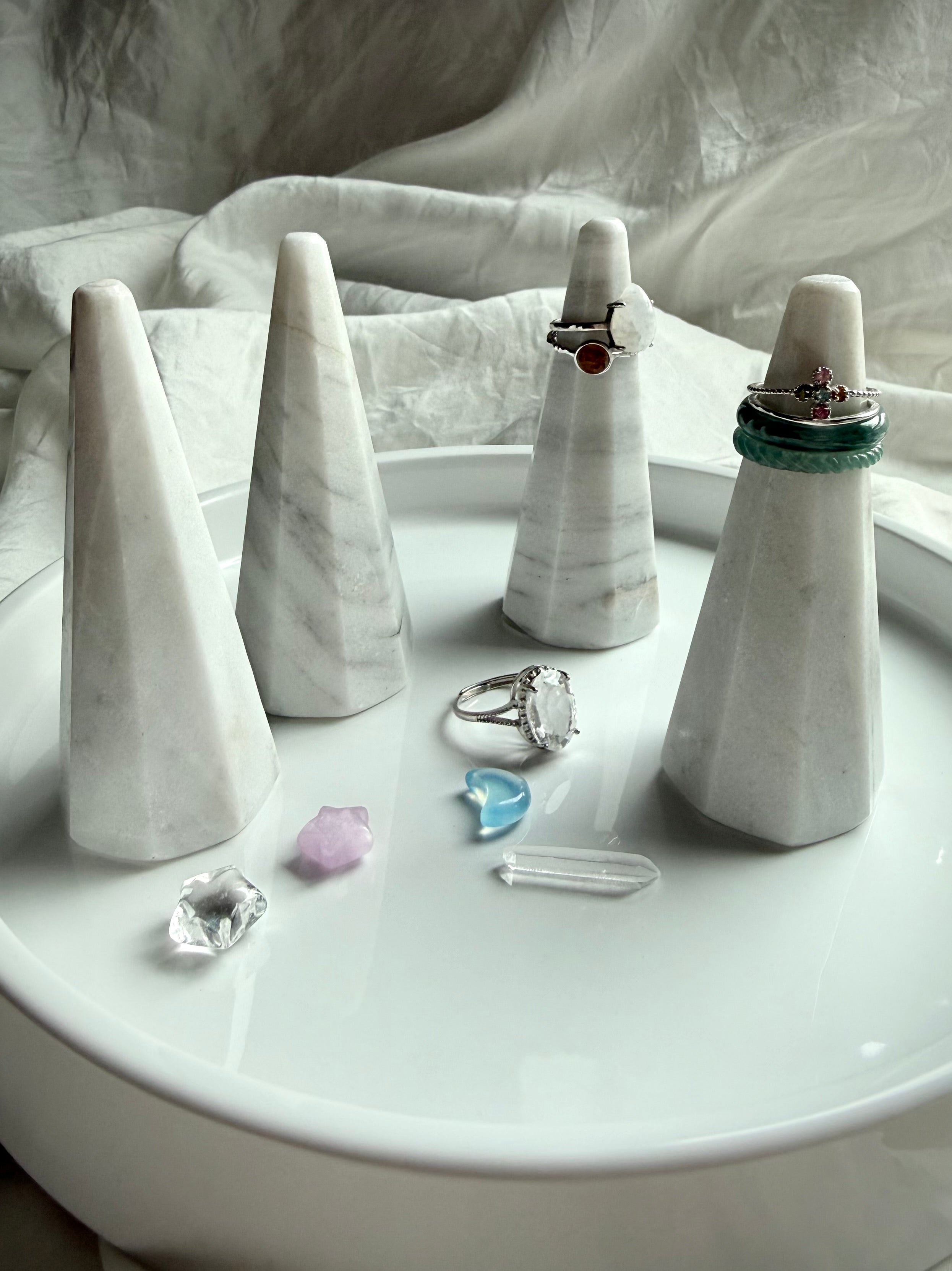 White and gray marble ring holders with faceted sculptural design displayed on vanity tray with rings