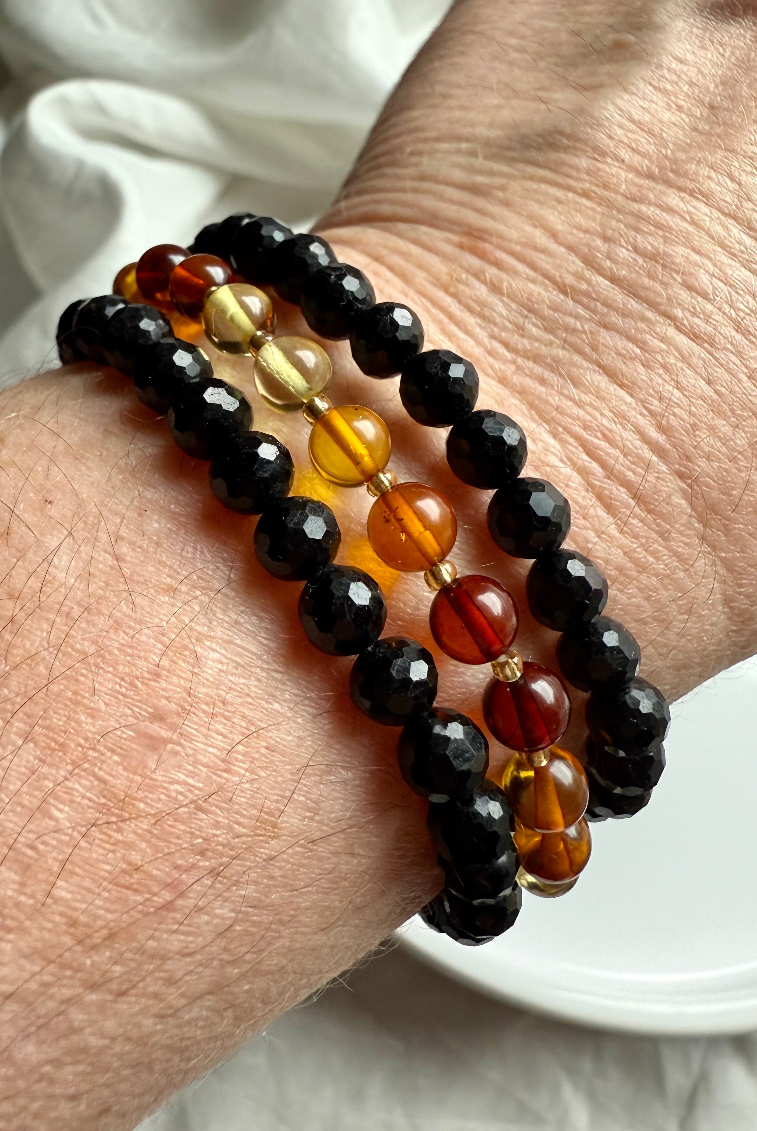 black tourmaline paired with golden Baltic amber bracelets for EMF protection, balance, and warmth