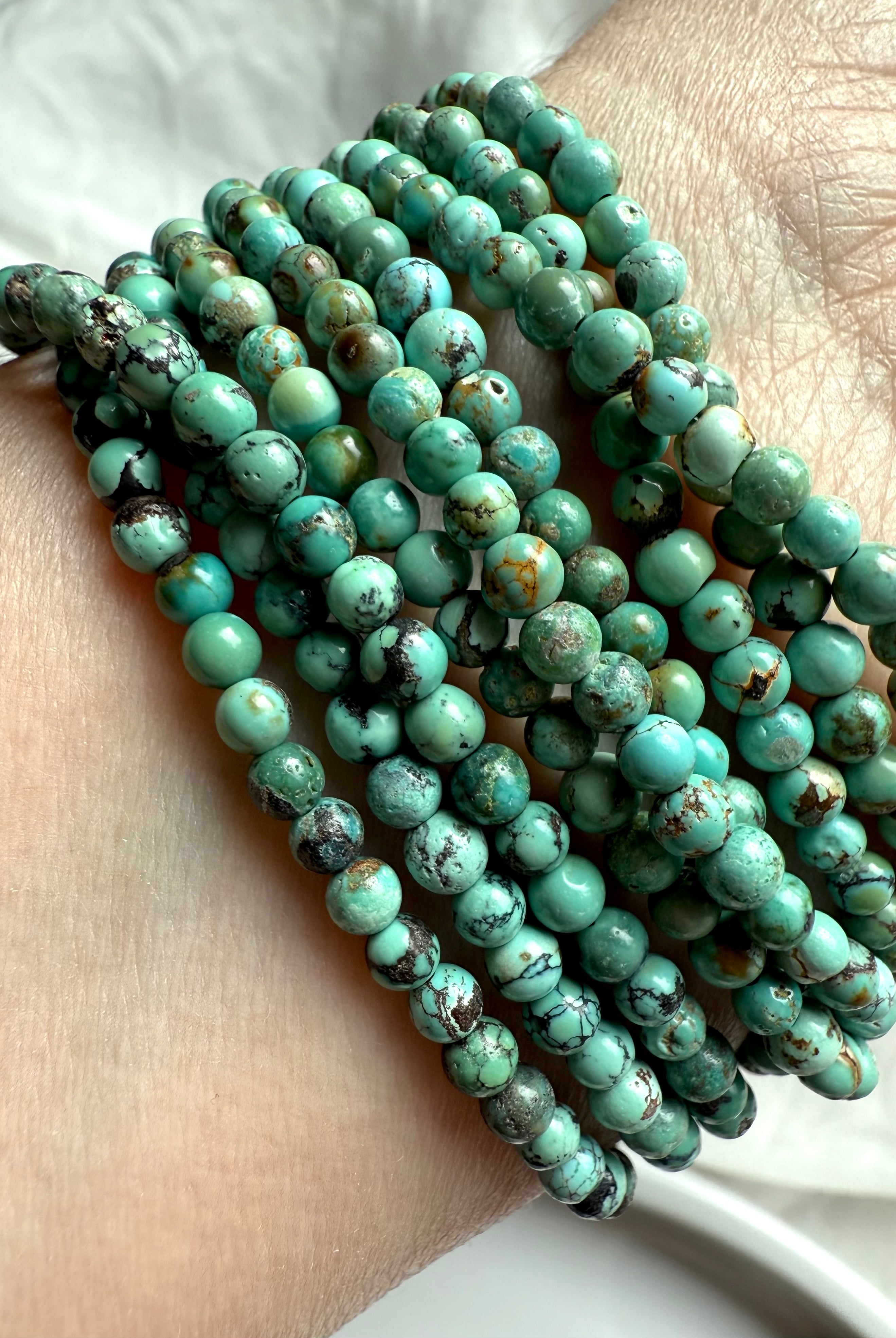 Close-up of stacked Turquoise wrap bracelets showcasing natural blue-green jasper beads with earthy veining and matrix patterns
