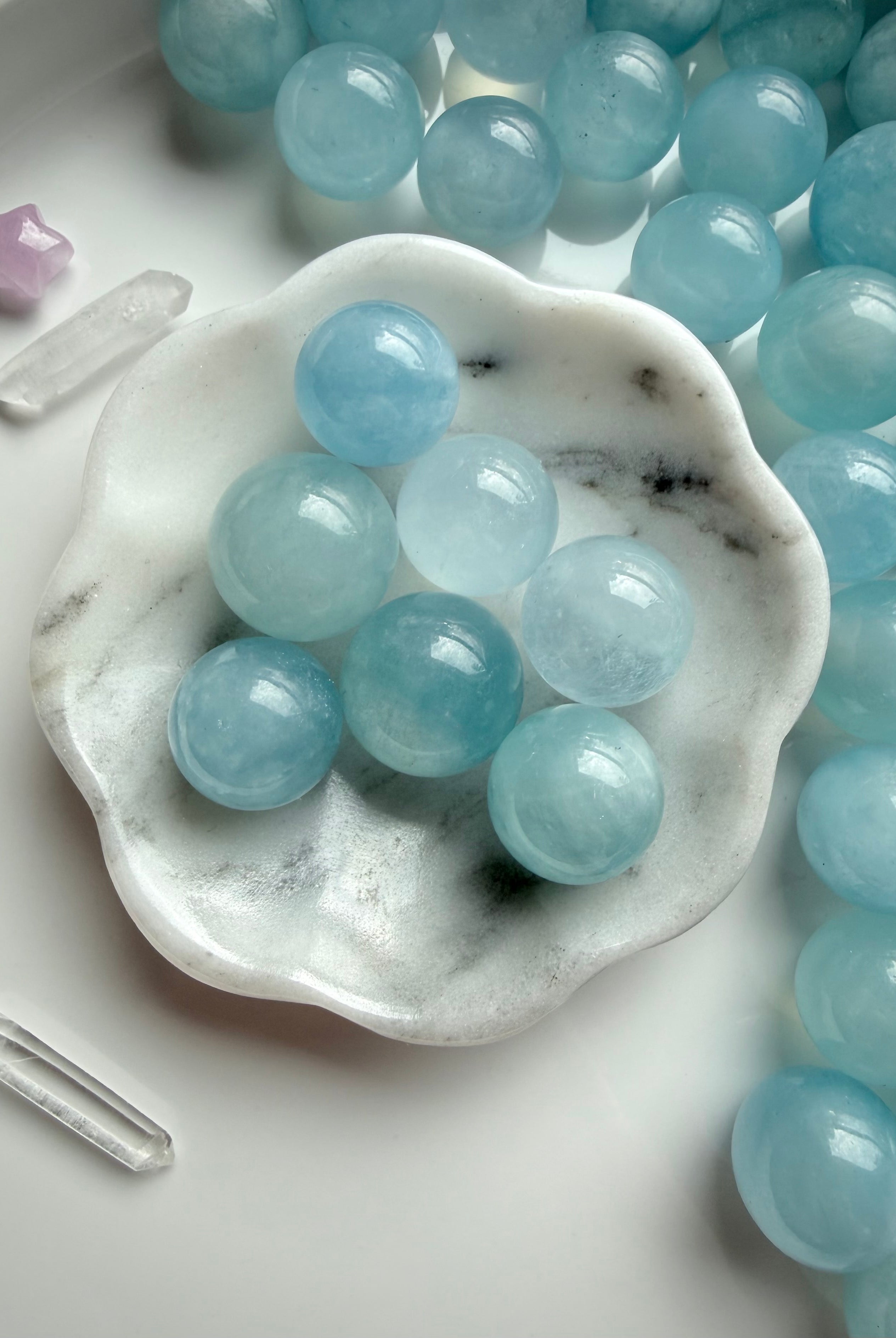 Aquamarine mini crystal spheres in calming ocean blue displayed in marble bowl – March birthstone crystal balls