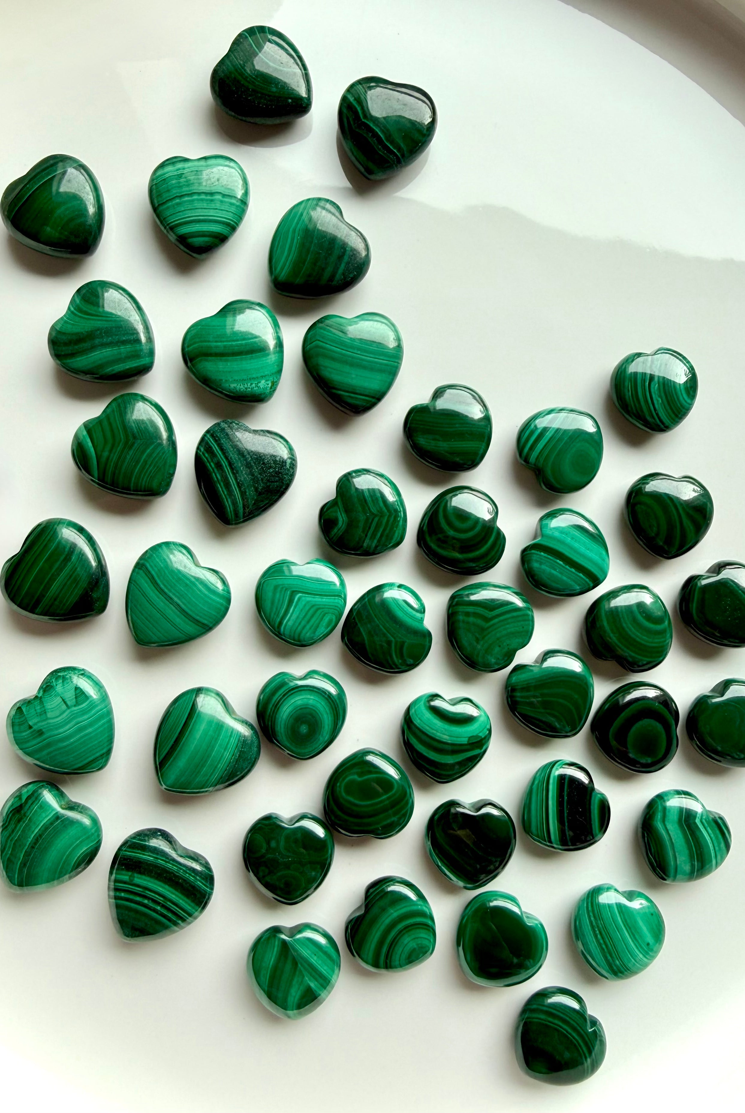 High-quality Mini Malachite crystal hearts on white with natural green banding and swirling patterns