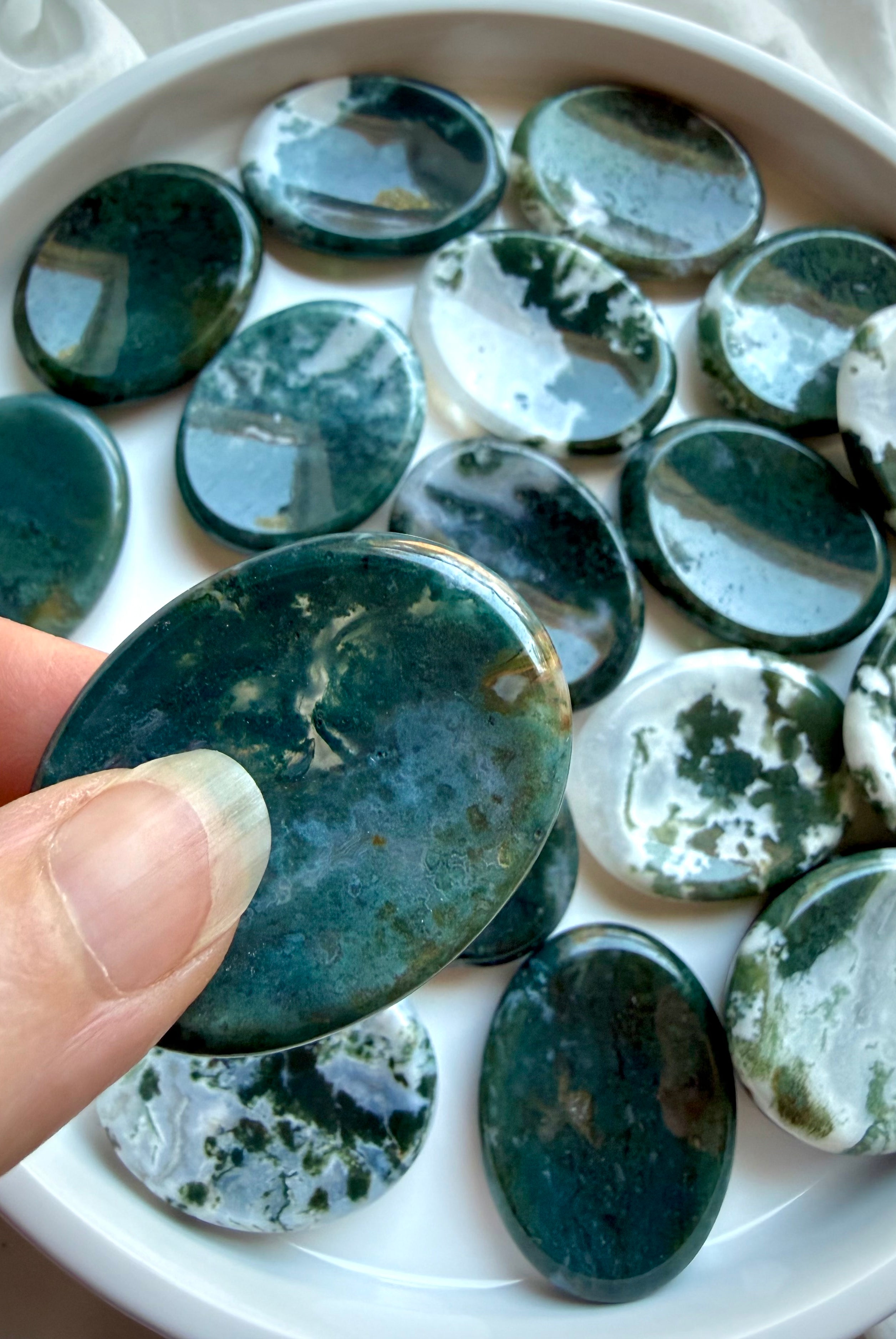 Dark green Moss Agate oval worry stone held in hand with natural moss inclusions and polished finish