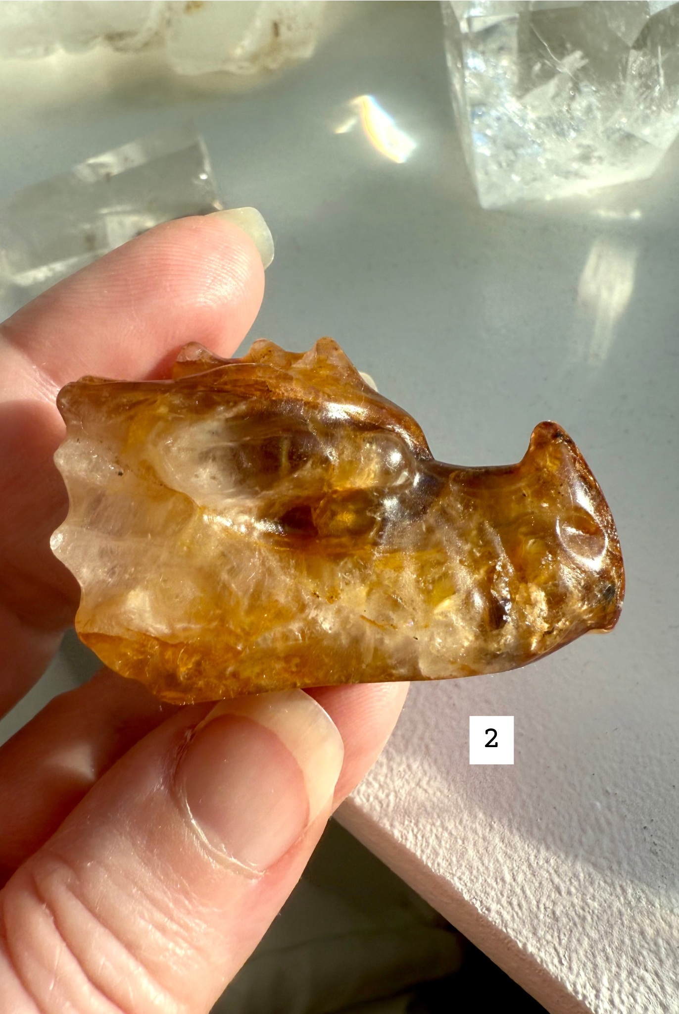 Golden Healer Quartz dragon head carving with dark golden hues, shown in hand — polished crystal dragon figurine for protection and empowerment.