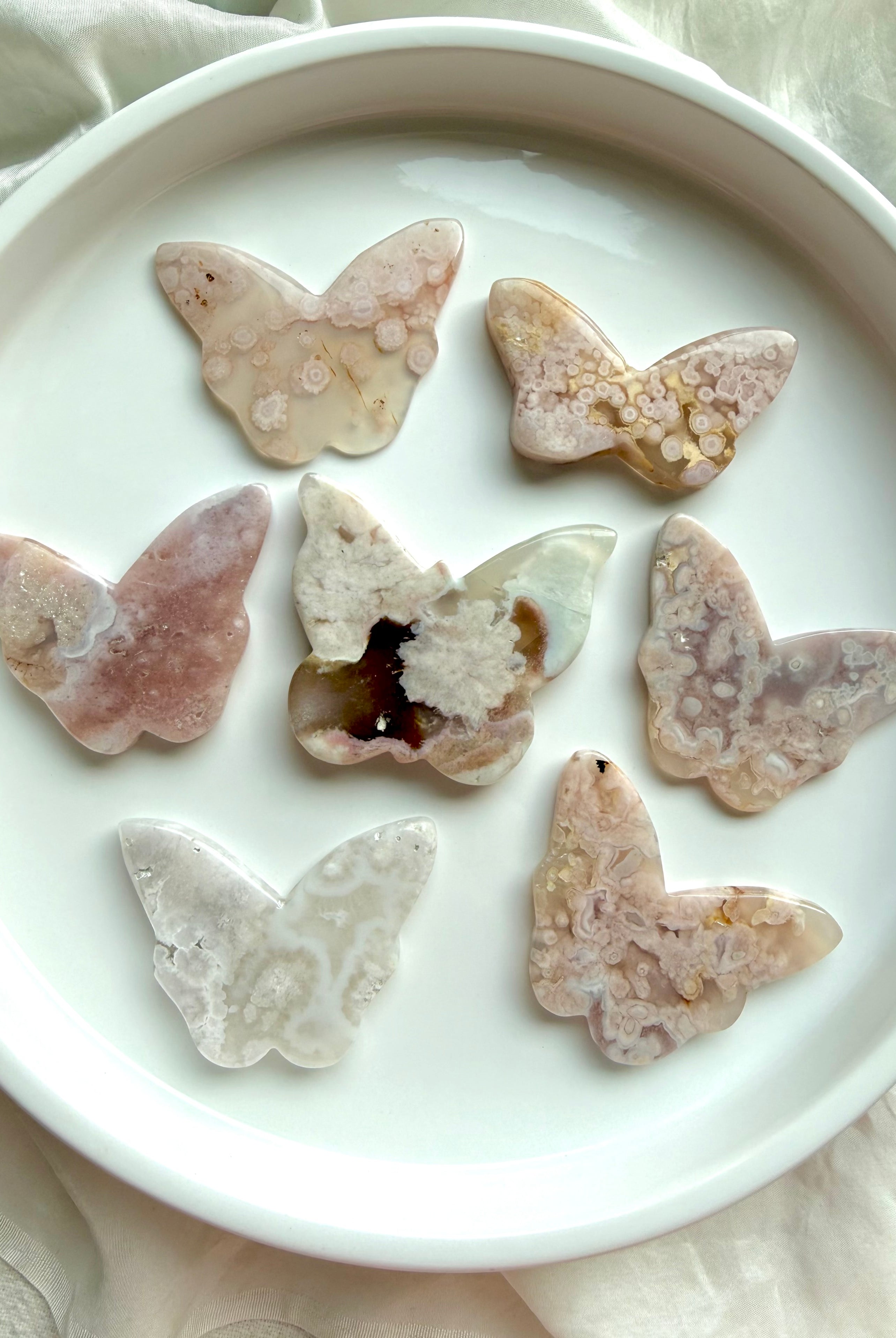 Flower Agate butterfly crystal carvings in soft pink blossom agate on white dish – choose your own butterfly crystal