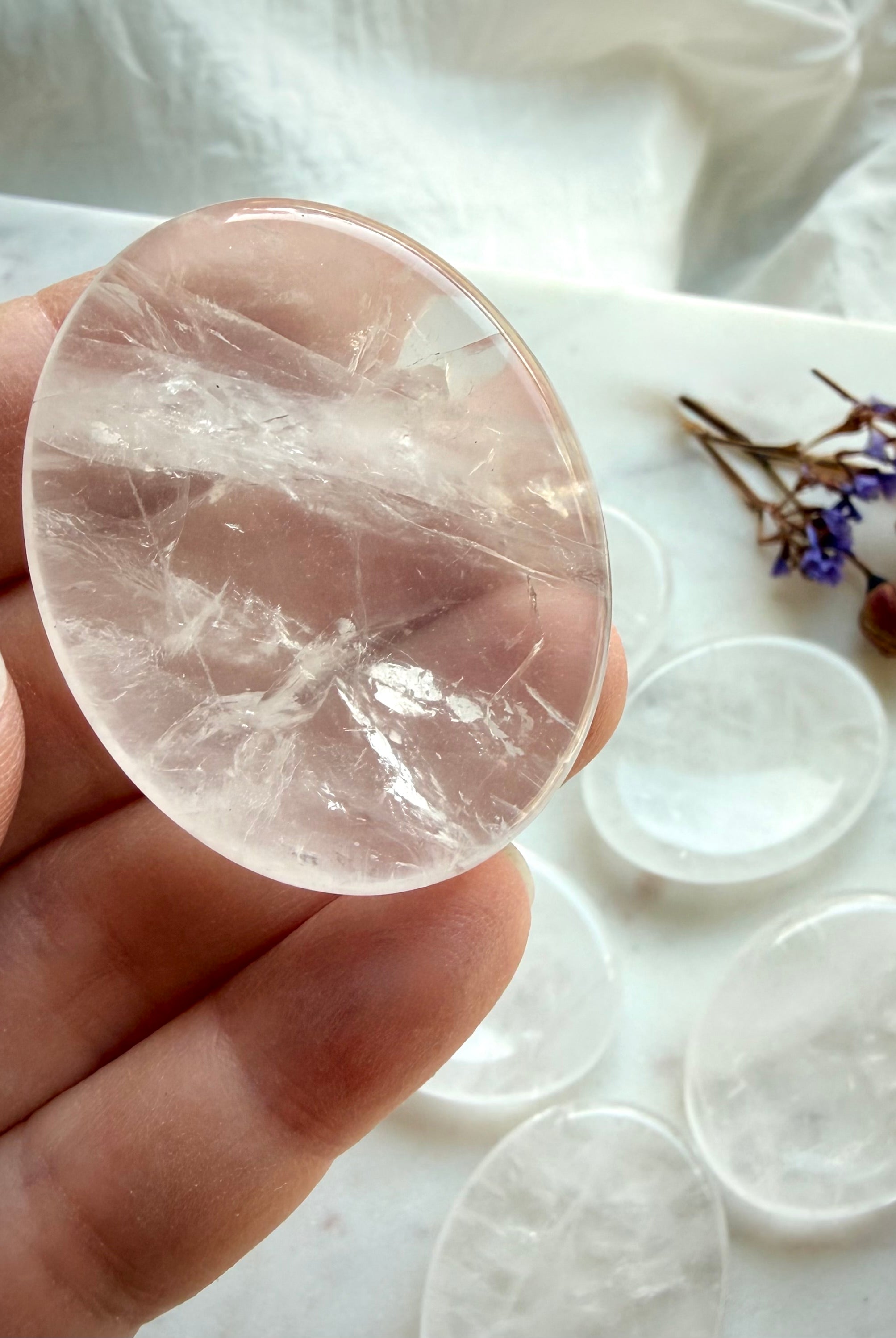 closeup of a clear quartz worry stone in hand showing oval shape for clarity focus & energy healing