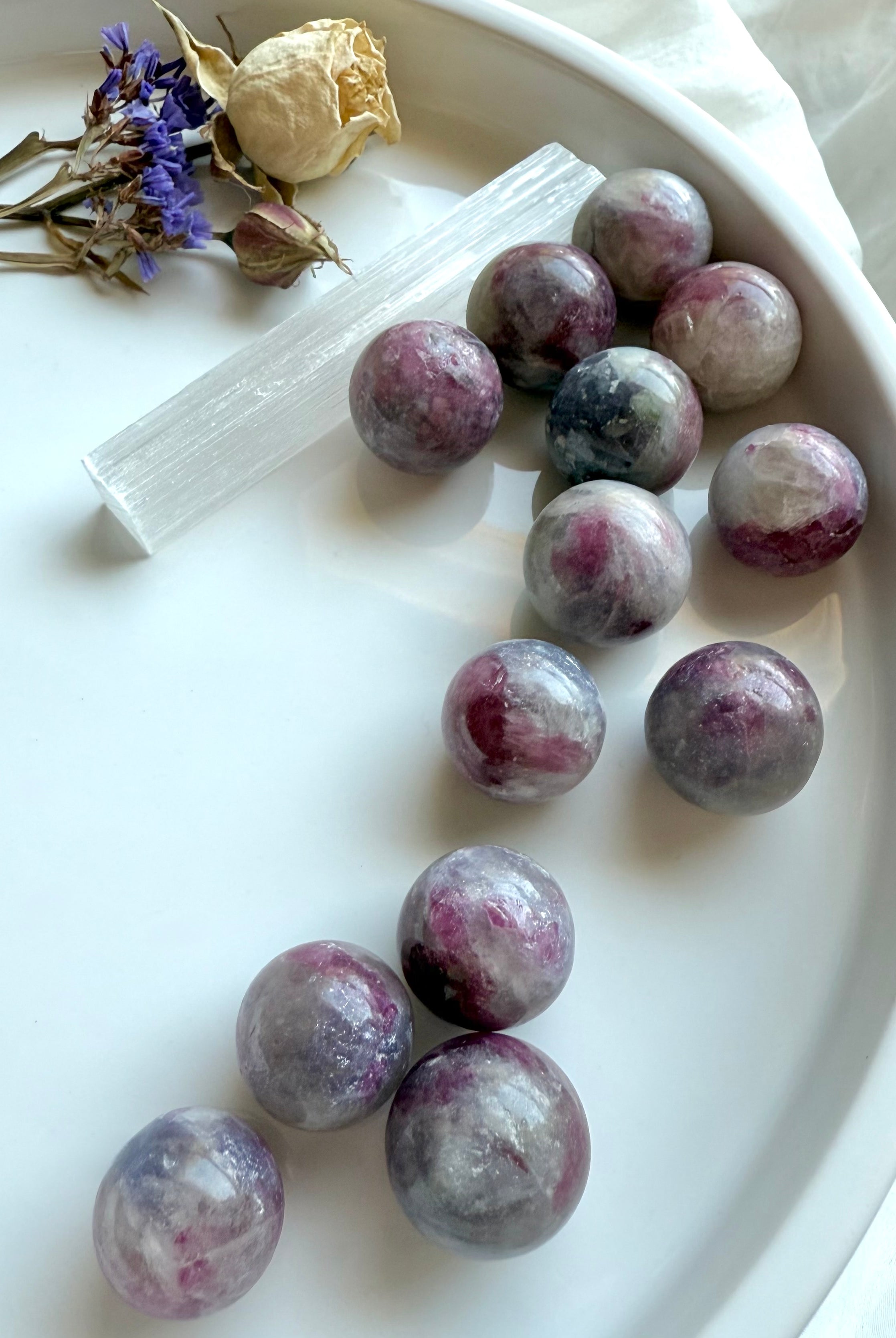 Mini Unicorn Stone spheres styled in a white tray with selenite wand, dried rose, and purple statice flowers